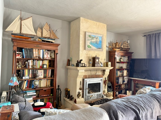 Salón con chimenea de piedra y estanterías de madera clásica. Destacan los detalles náuticos y la colección de libros en un ambiente acogedor y tradicional.