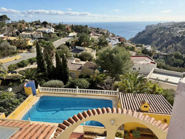 Vista elevada de la piscina de 10x4 m con balaustrada blanca, destacando las vistas panorámicas al mar Mediterráneo y al entorno costero de Benitachell.