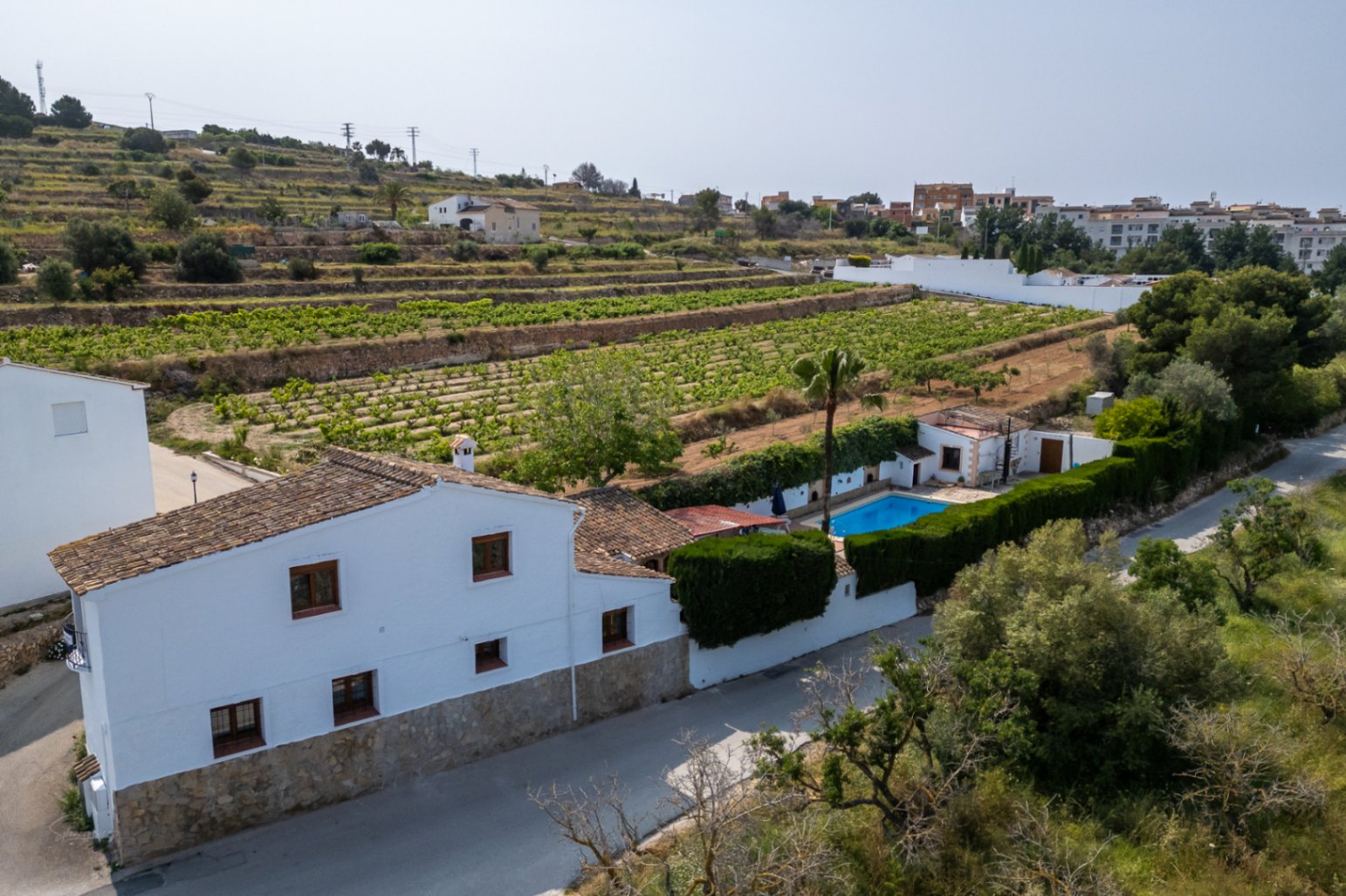 Vista aérea de casa de campo blanca con piscina, rodeada de viñedos en Teulada, Costa Blanca.