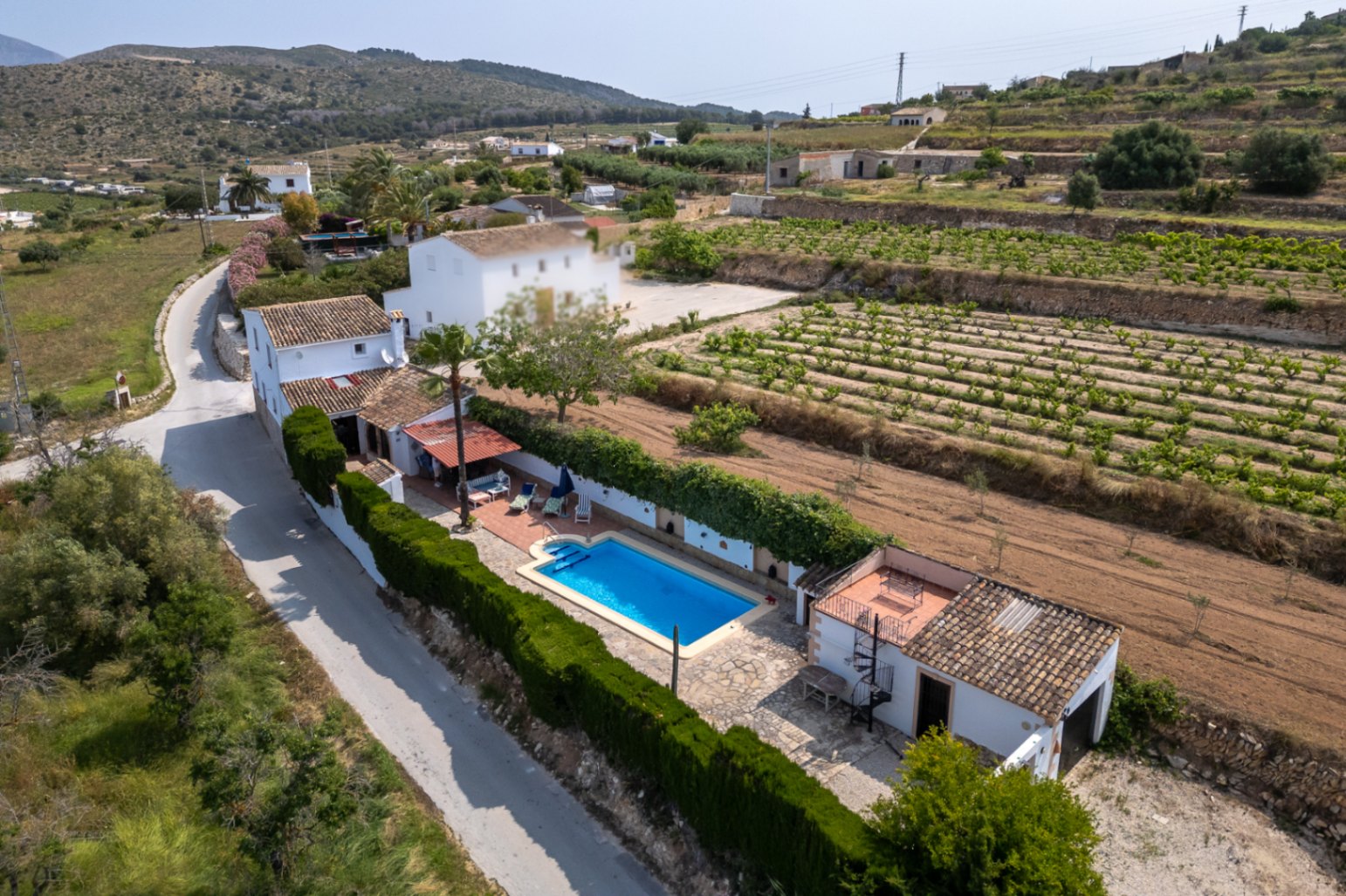 Vista aérea de finca con piscina azul, jardín maduro y campos cultivados en Teulada, Costa Blanca.