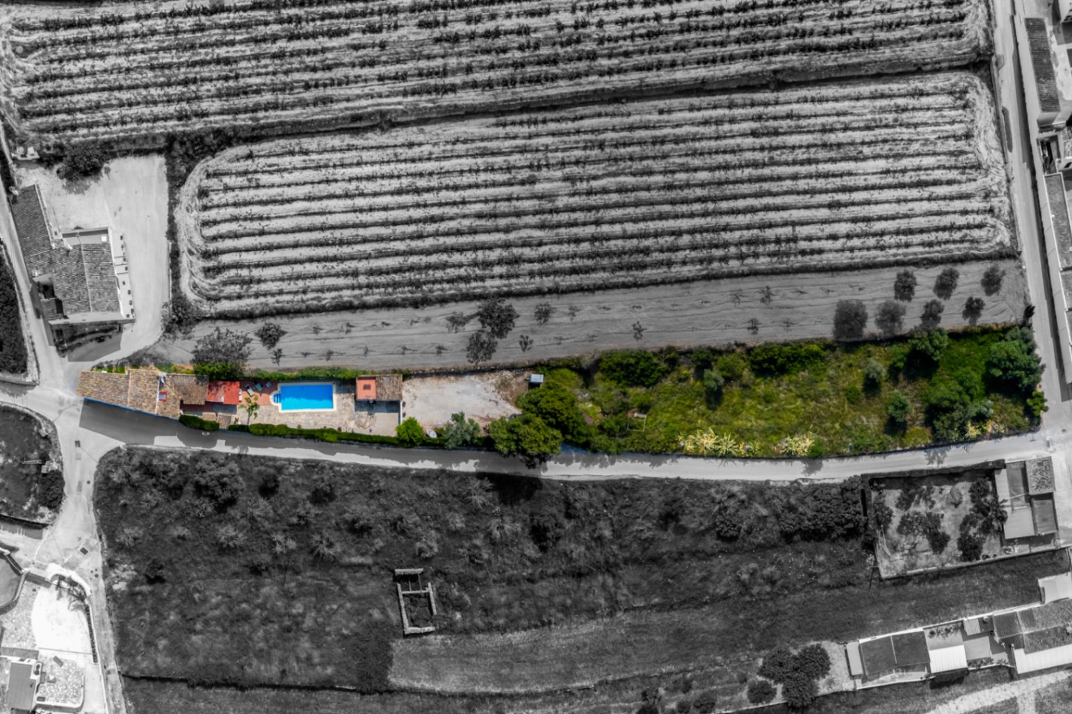 Vista aérea de finca con piscina en Teulada, rodeada de campos y vegetación.