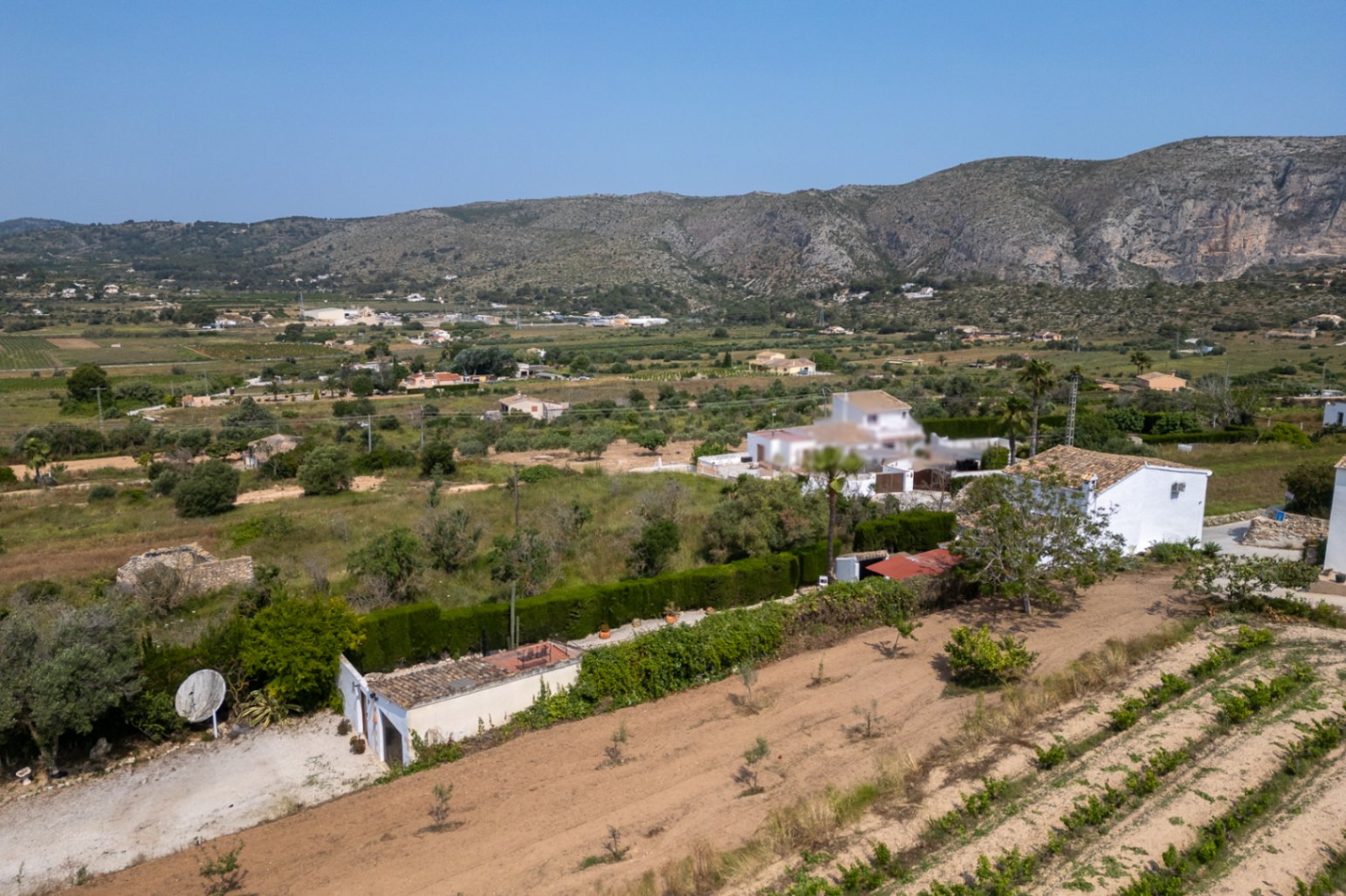 Vista aérea de la finca en Teulada con terreno cultivado y edificación blanca.
