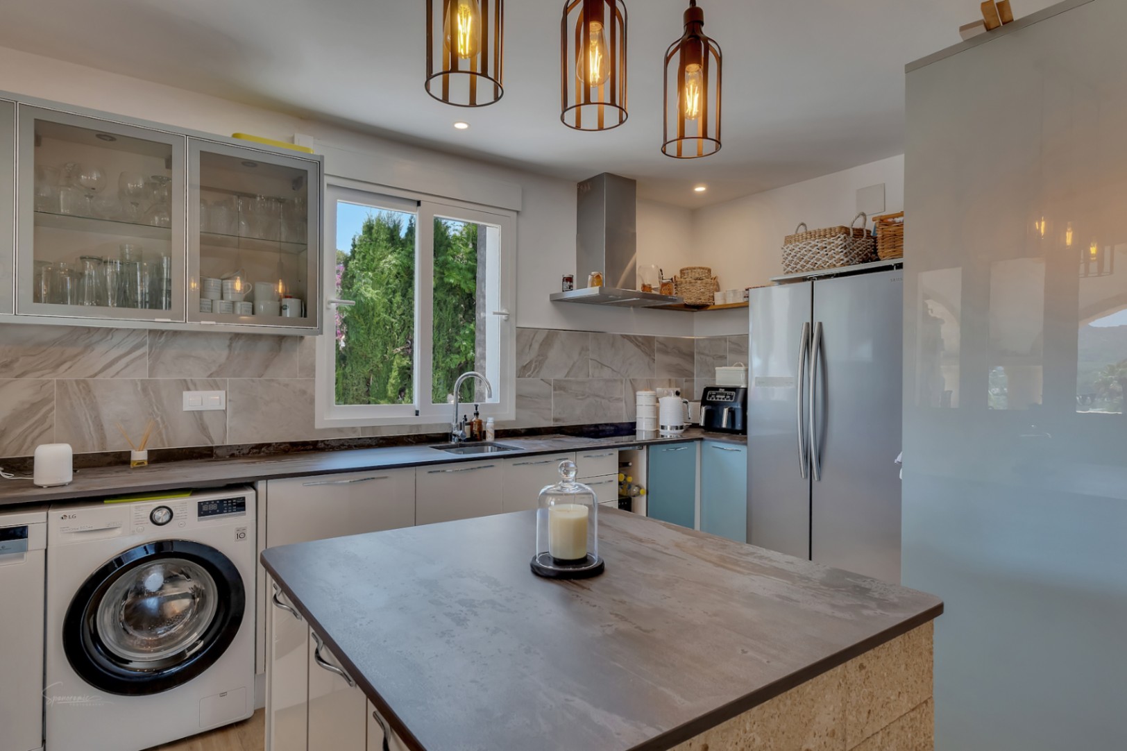Cocina moderna con isla central, electrodomésticos integrados y luz colgante de diseño.