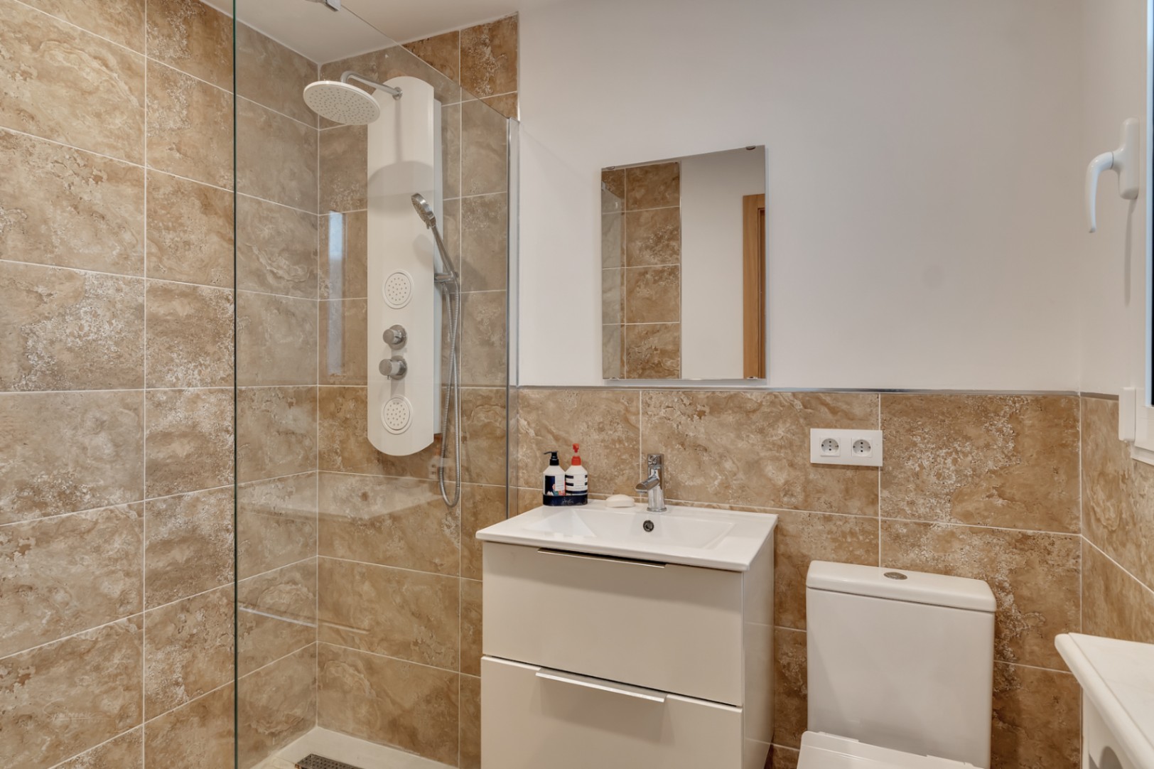 Detalle de baño con ducha moderna y revestimiento cerámico en tonos tierra.