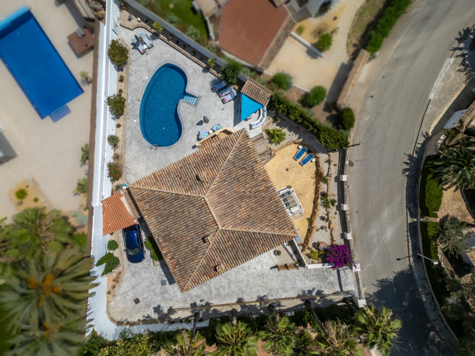 Vista aérea de villa con piscina, terraza y tejado de tejas rojas. Aparcamiento privado visible.