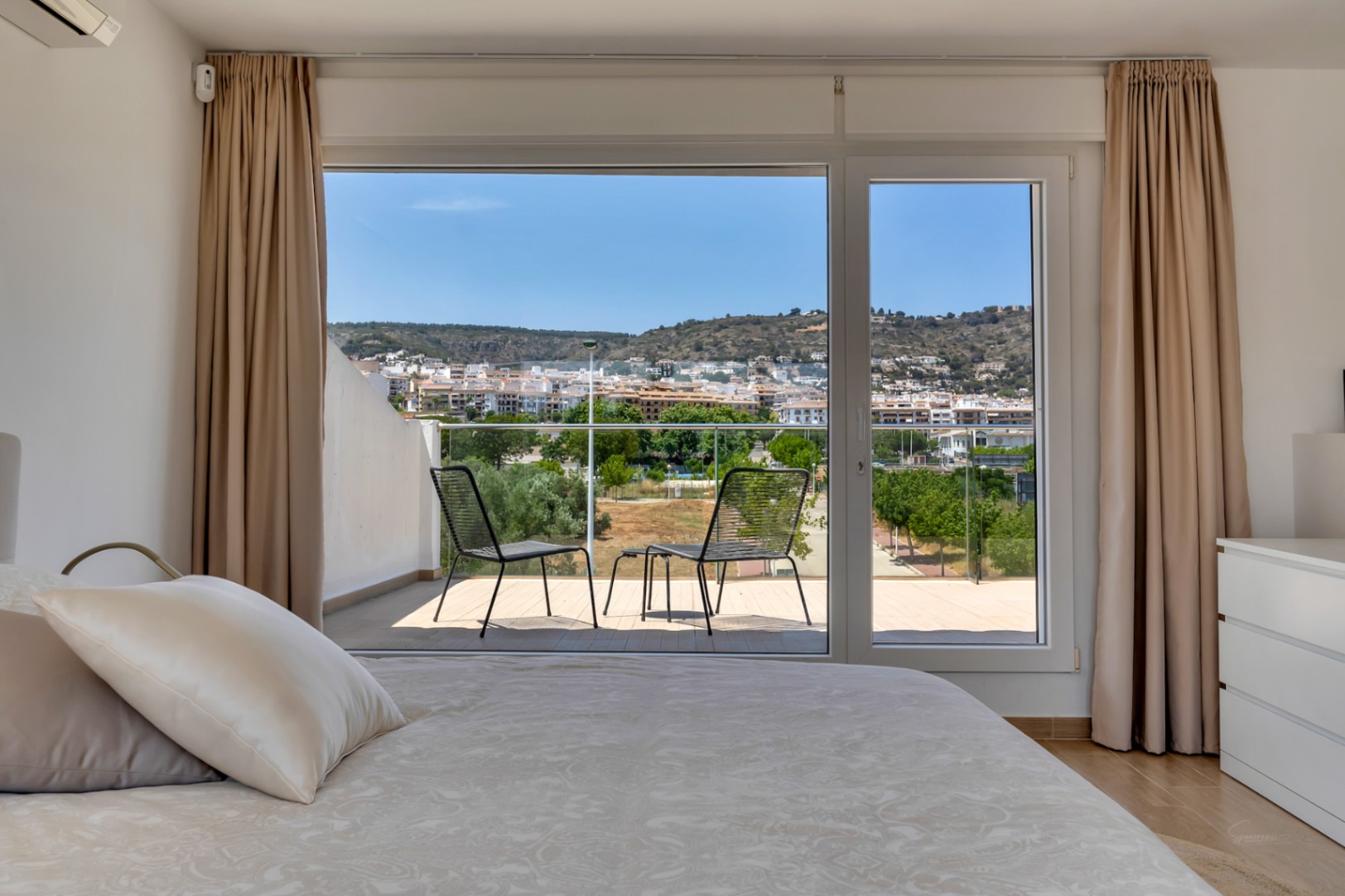 Dormitorio con acceso a terraza privada, vistas panorámicas al entorno y colinas. Dispone de aire acondicionado y grandes ventanales que aportan abundante luz natural.
