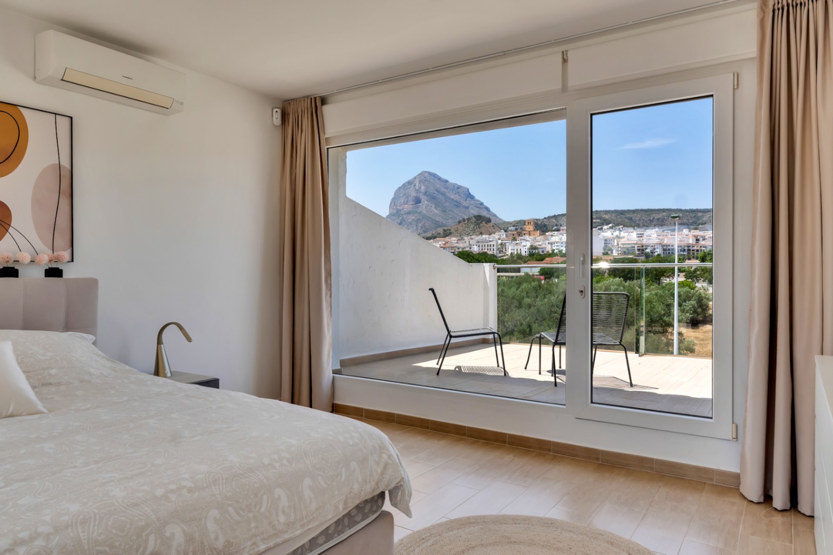 Dormitorio principal con acceso a terraza privada y vistas despejadas al Montgó. Incluye suelos cerámicos, aire acondicionado y grandes ventanales.