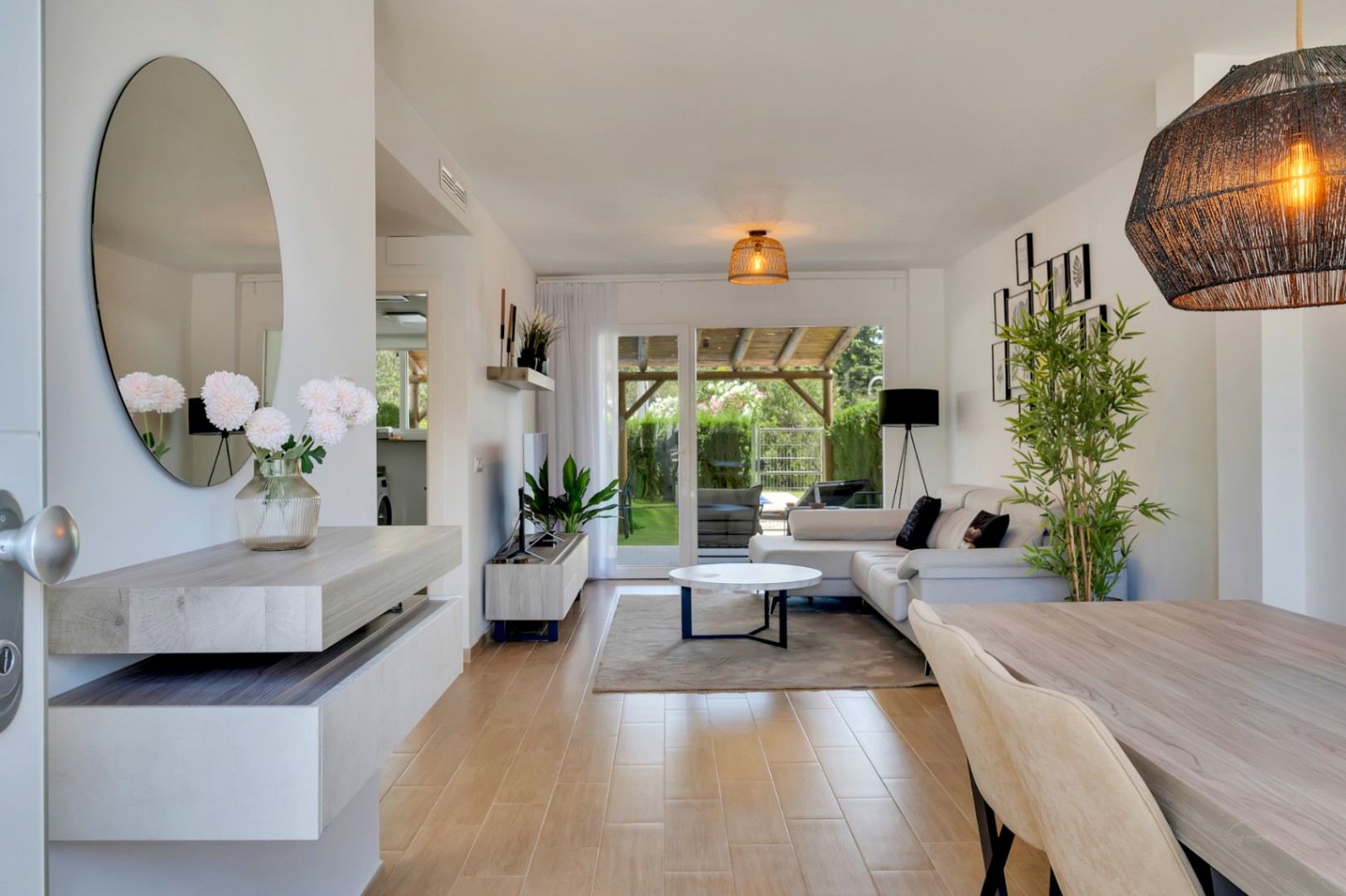 Salón-comedor de concepto abierto con suelos de gres efecto madera, mobiliario contemporáneo y acceso directo al patio privado a través de grandes puertas acristaladas.