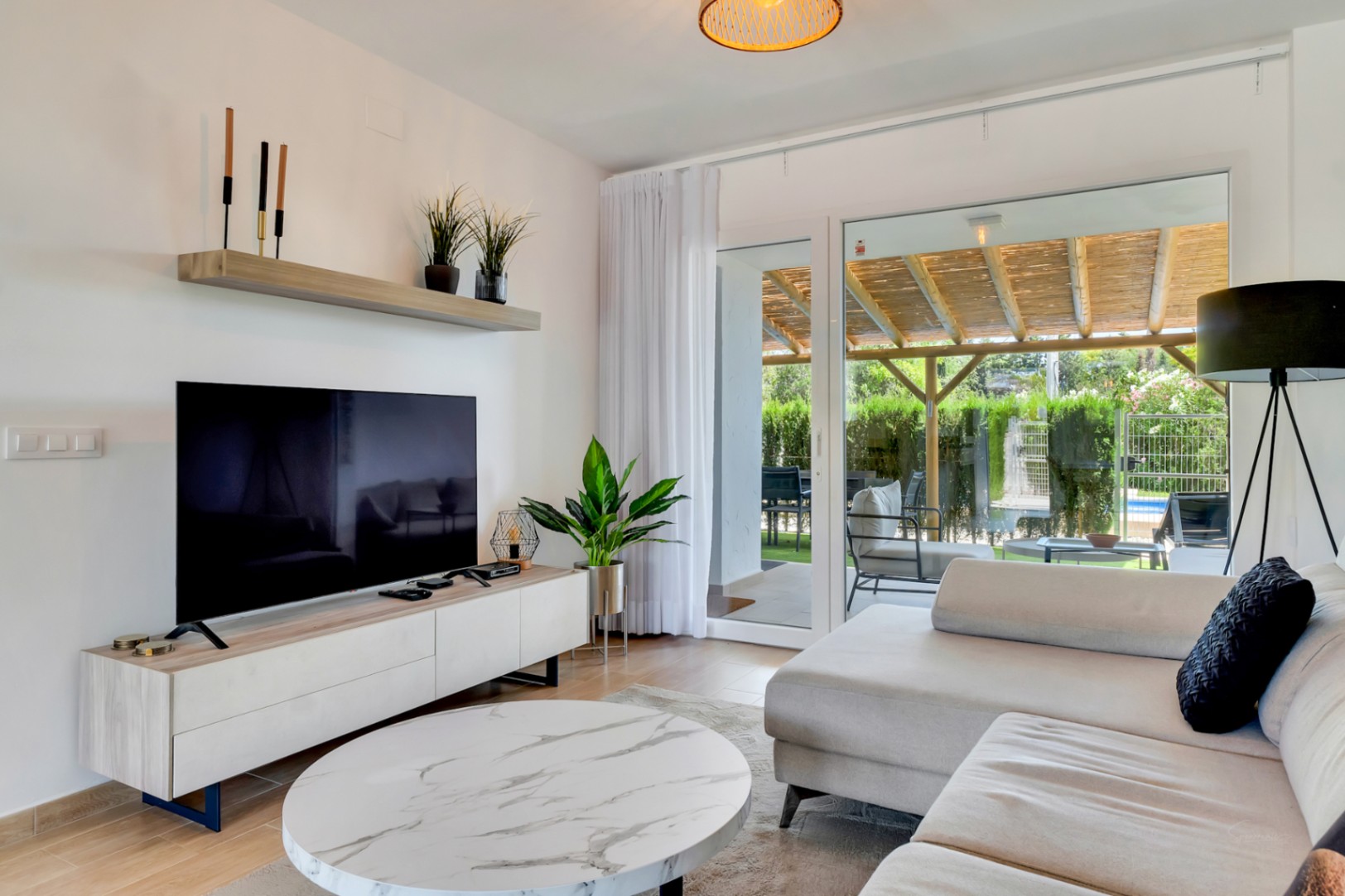 Salón de concepto abierto con mobiliario contemporáneo y grandes ventanales que conectan directamente con el patio privado y la zona de la pérgola.
