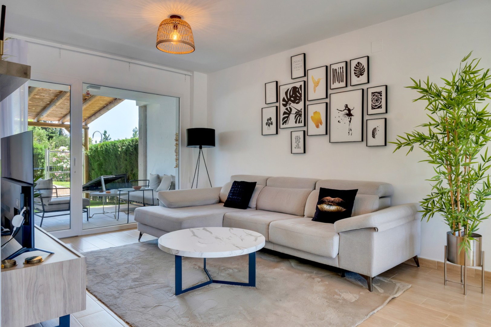 Salón de concepto abierto con sofá rinconero moderno, mesa de mármol y grandes ventanales que conectan directamente con el patio privado.