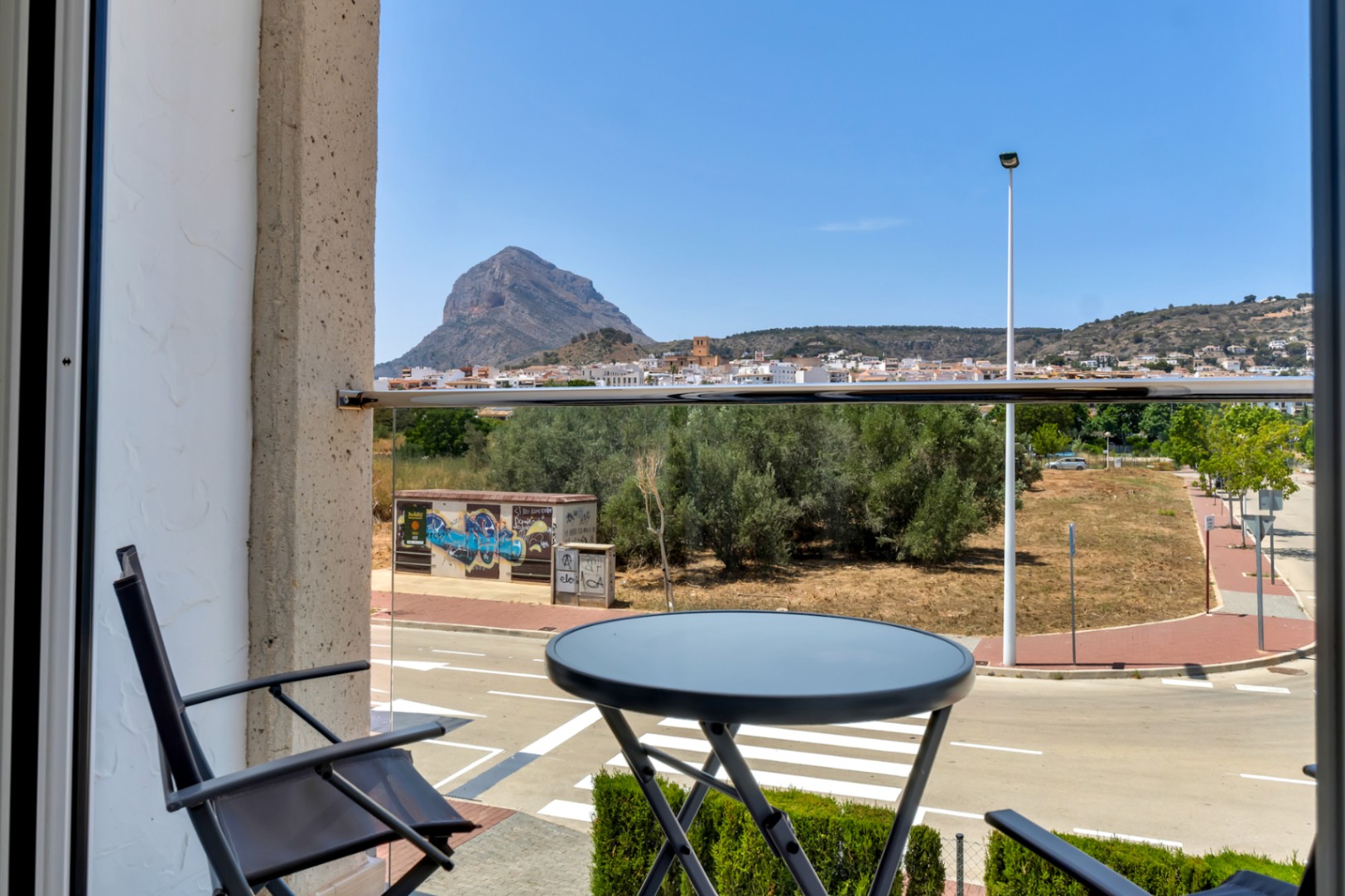 Vistas despejadas al Montgó y al casco antiguo desde el balcón privado, equipado con barandilla de cristal y mobiliario de exterior minimalista.