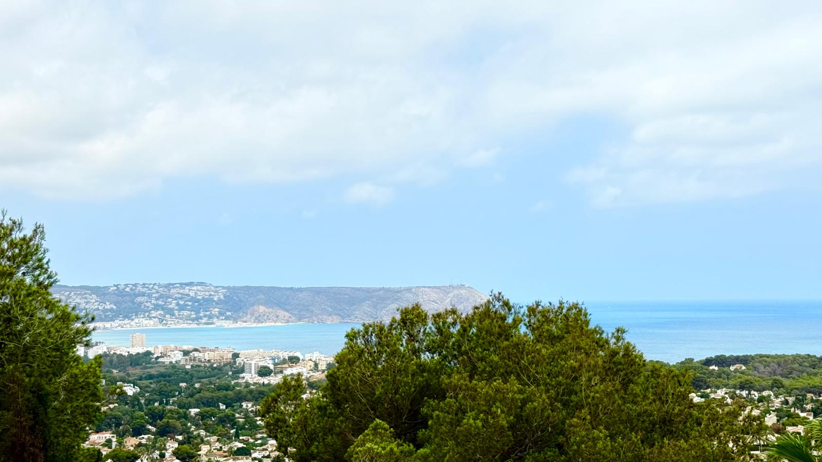 Vistas panorámicas de la bahía de Jávea y el mar Mediterráneo, con el cabo de San Antonio en el horizonte, enmarcadas por la vegetación autóctona de la parcela.