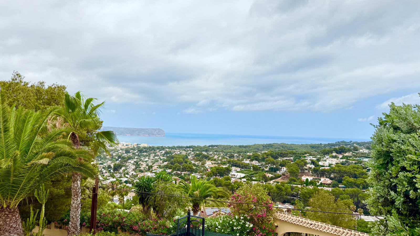 Vistas panorámicas desde la propiedad hacia la bahía de Jávea y el mar Mediterráneo, enmarcadas por la vegetación madura del jardín y el Cabo de San Antonio al fondo.