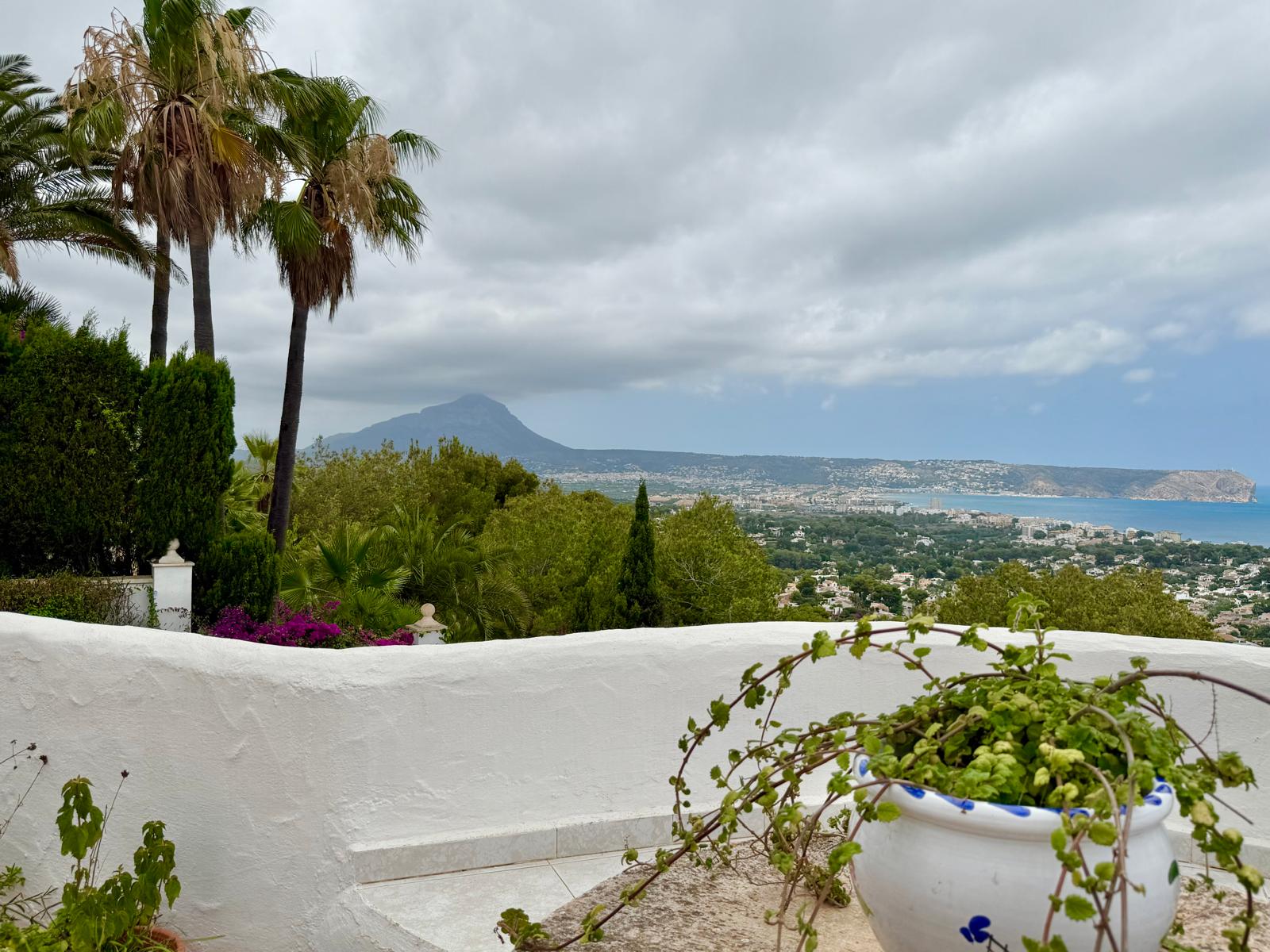 Vistas panorámicas desde la terraza hacia la bahía de Jávea y el Montgó, enmarcadas por vegetación mediterránea y muros blancos de estilo ibicenco.