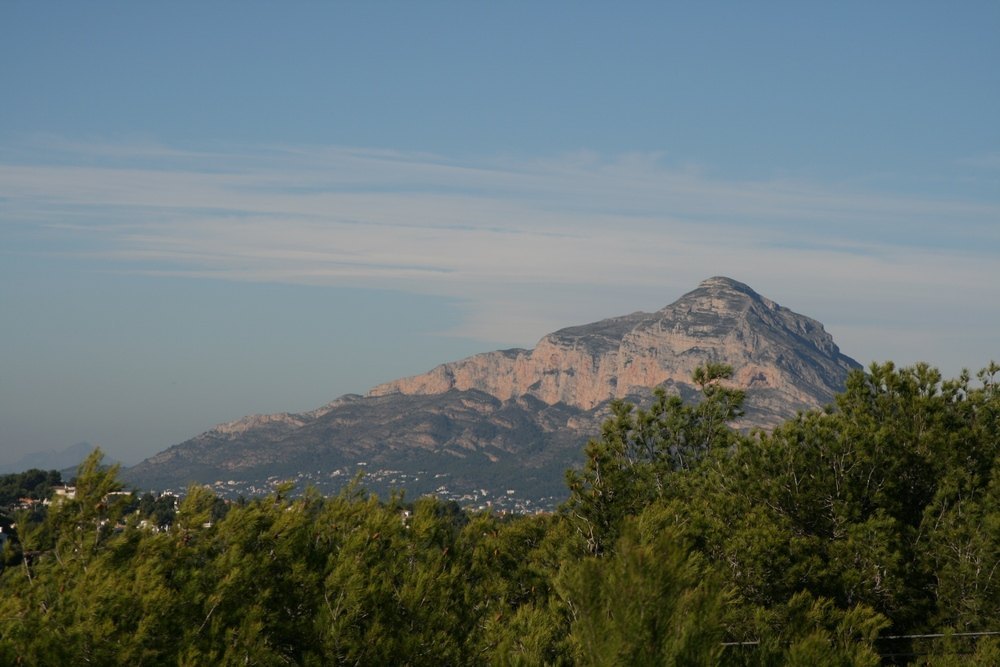 Vista panorámica del macizo del Montgó desde la parcela, destacando el relieve rocoso sobre un entorno de pinos mediterráneos bajo un cielo despejado.