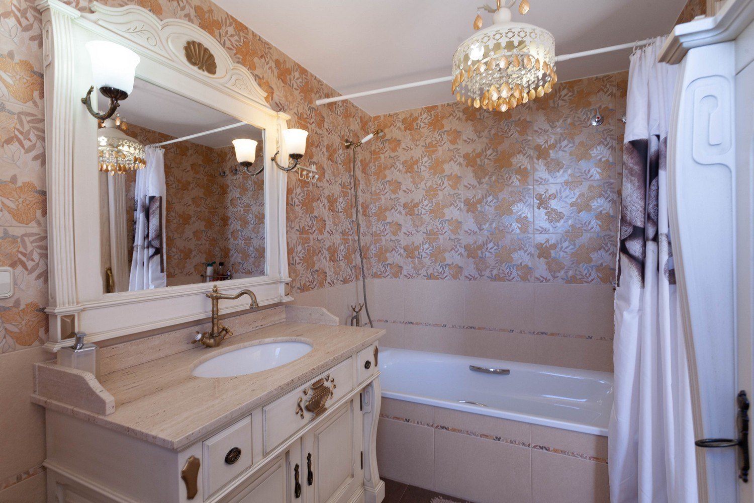 Cuarto de baño clásico con lavabo de mármol, espejo ornamentado y bañera con ducha.