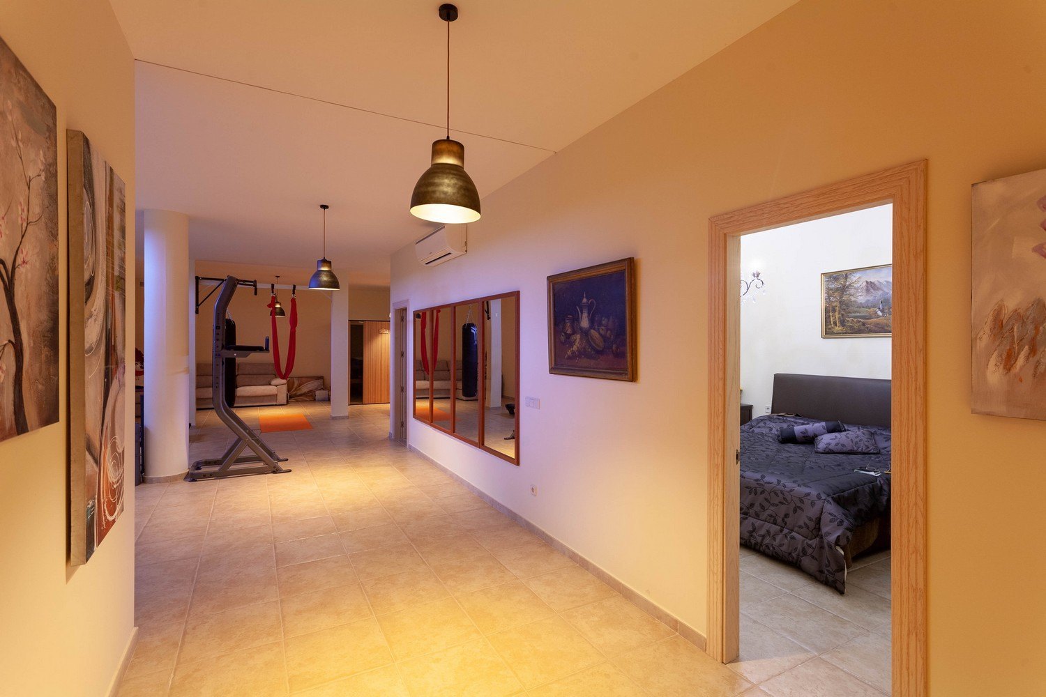 Interior luminoso con gimnasio, sauna y acceso al dormitorio. Suelo de baldosas y decoración clásica.