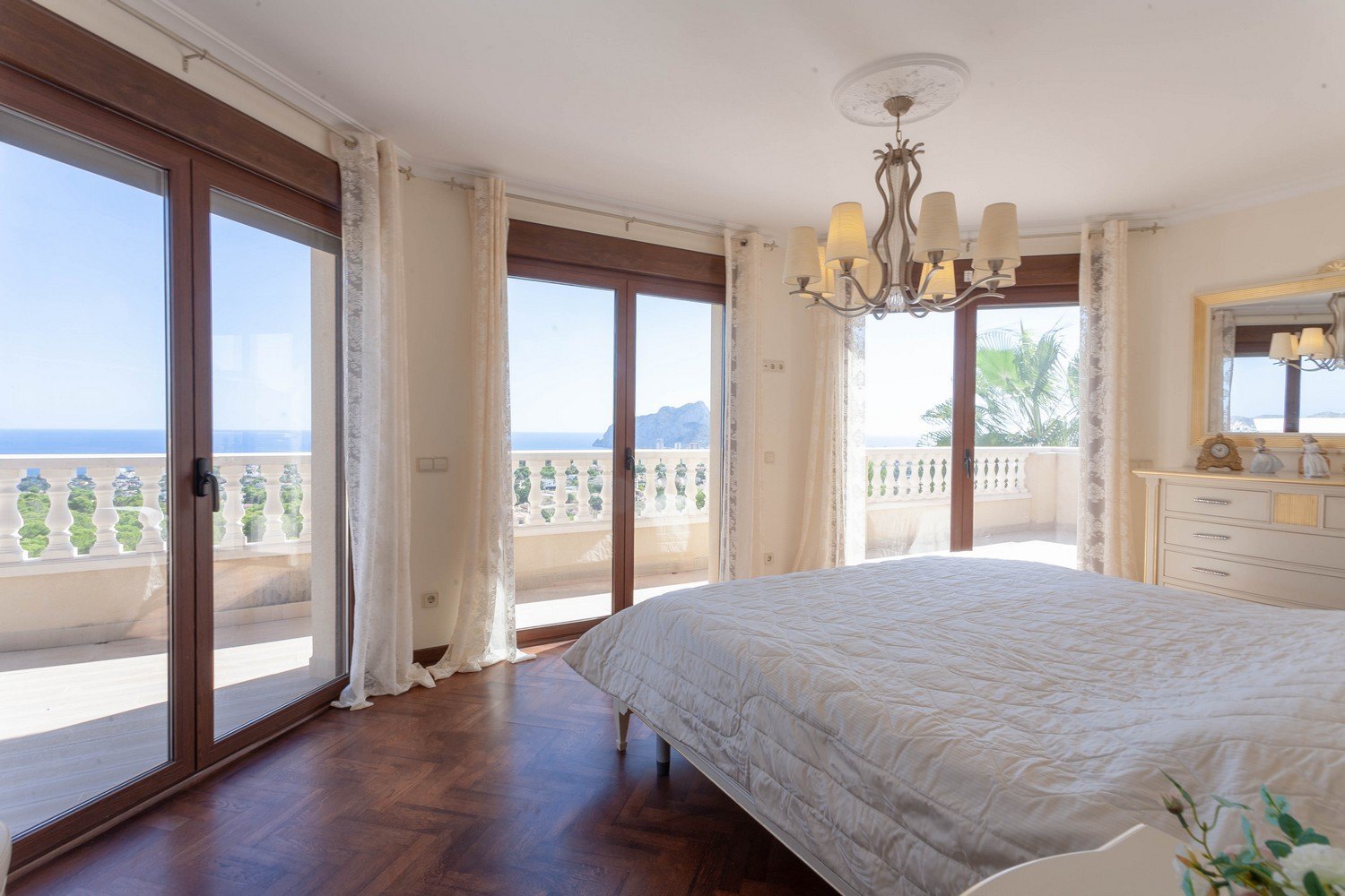 Luminoso dormitorio con vistas al mar, balcón con balaustrada y suelo de parquet en espiga.