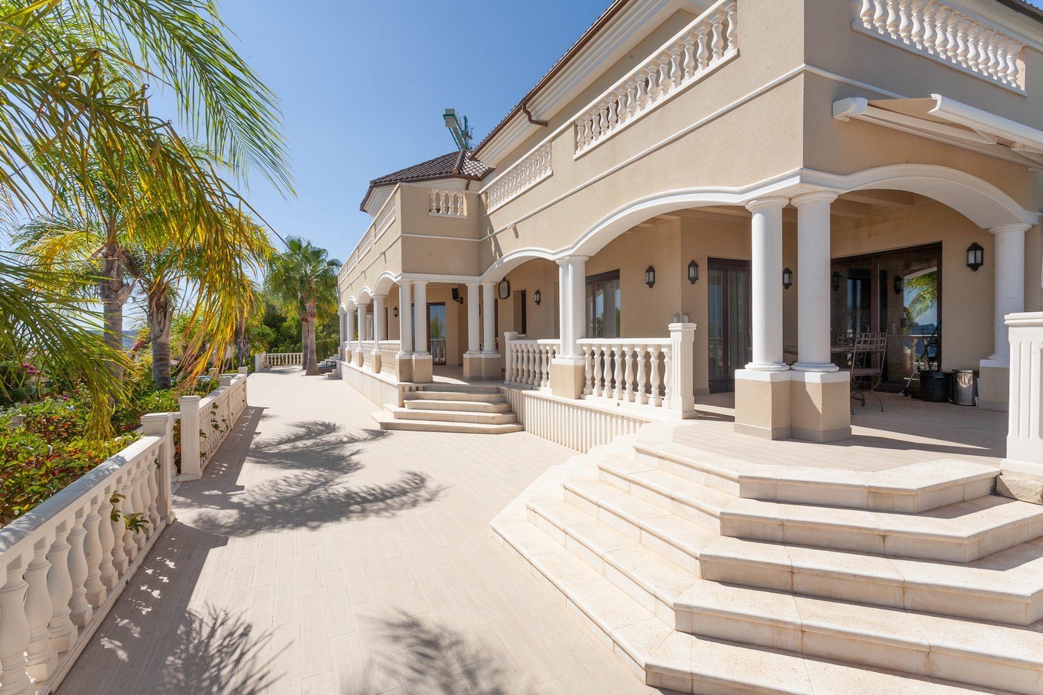 Vista exterior de la villa con terraza de piedra y barandilla clásica.