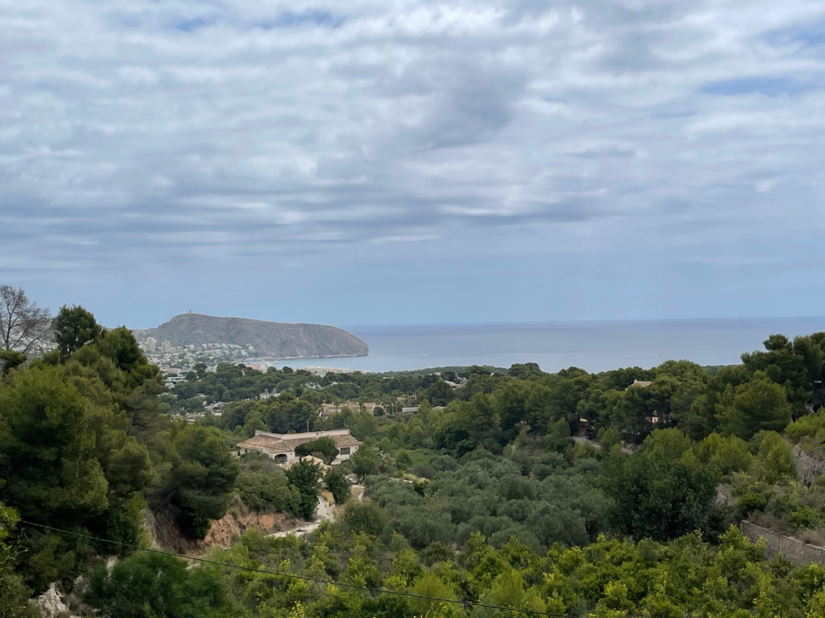 Vista panorámica desde la parcela en Benimeit, mostrando el valle arbolado hacia el mar Mediterráneo y el emblemático Cap d'Or de Moraira.