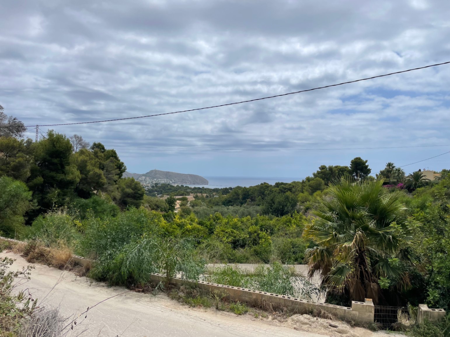 Vistas panorámicas al mar Mediterráneo y al cabo de Moraira desde la parcela elevada, rodeada de pinos y vegetación autóctona.