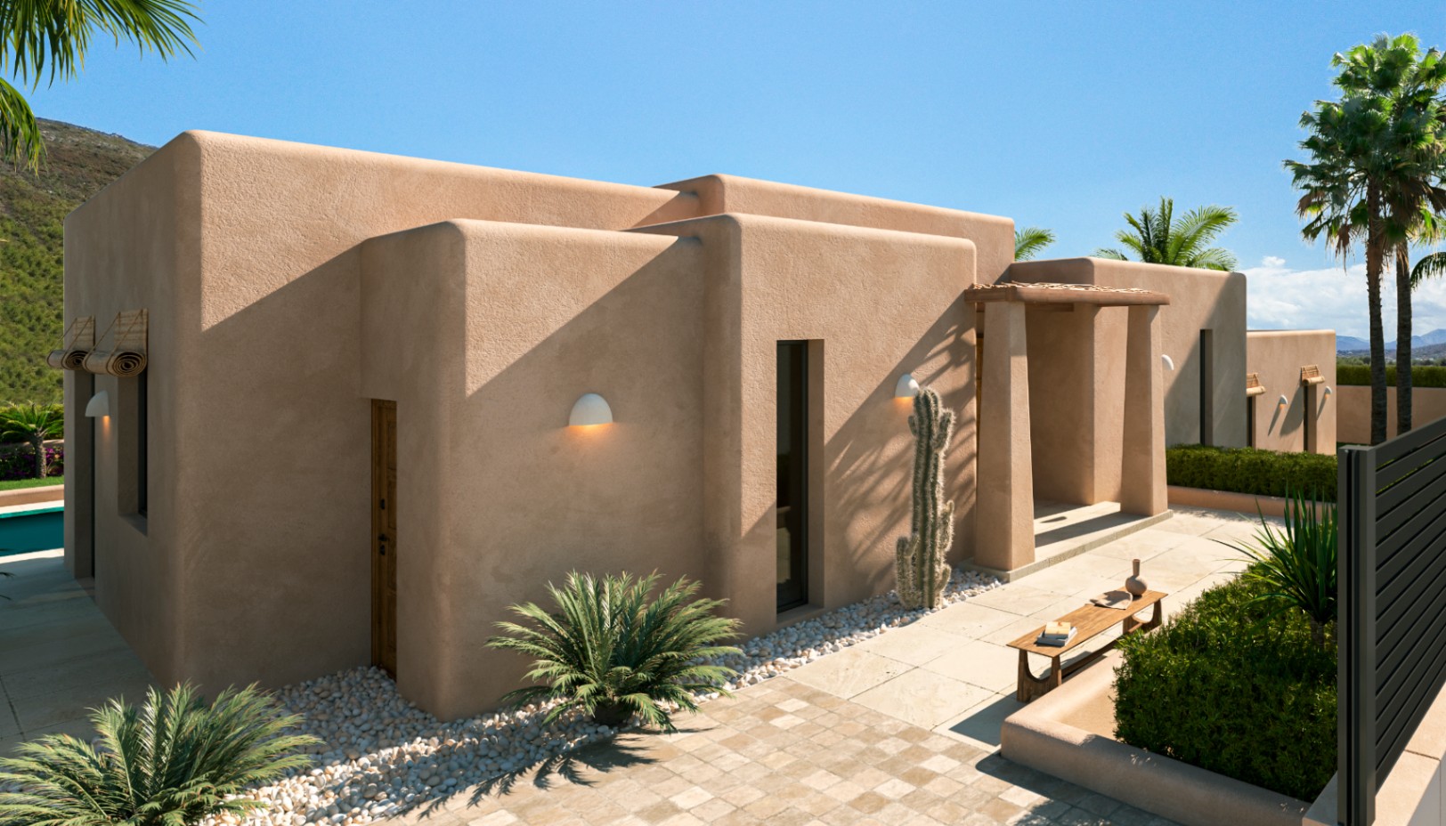 Fachada exterior de estilo mediterráneo contemporáneo con acabados en tonos tierra, jardinería xerófila con cactus y palmeras sobre senderos de piedra natural.