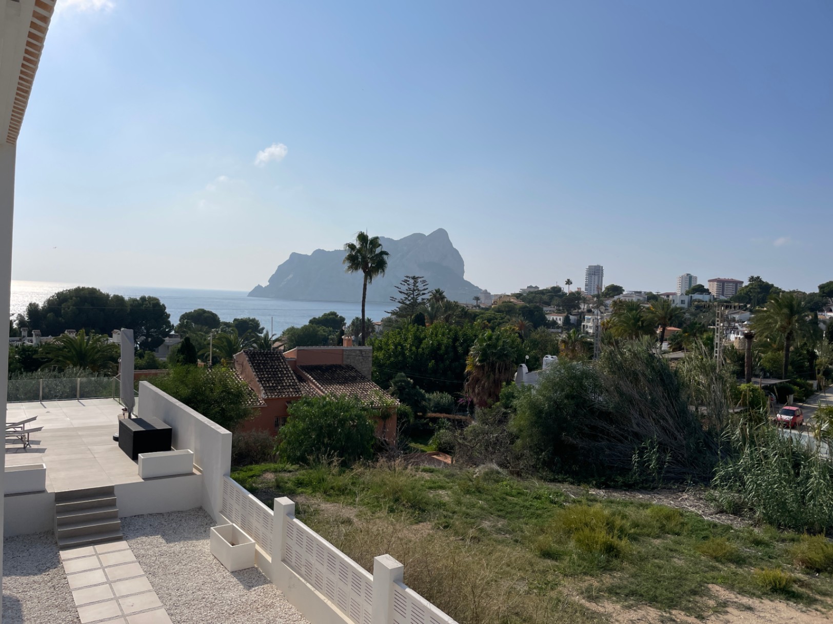 Vista panorámica del Peñón de Ifach y el Mediterráneo desde una terraza moderna con pavimentos claros, rodeada de vegetación autóctona en Bassetes, Calpe.