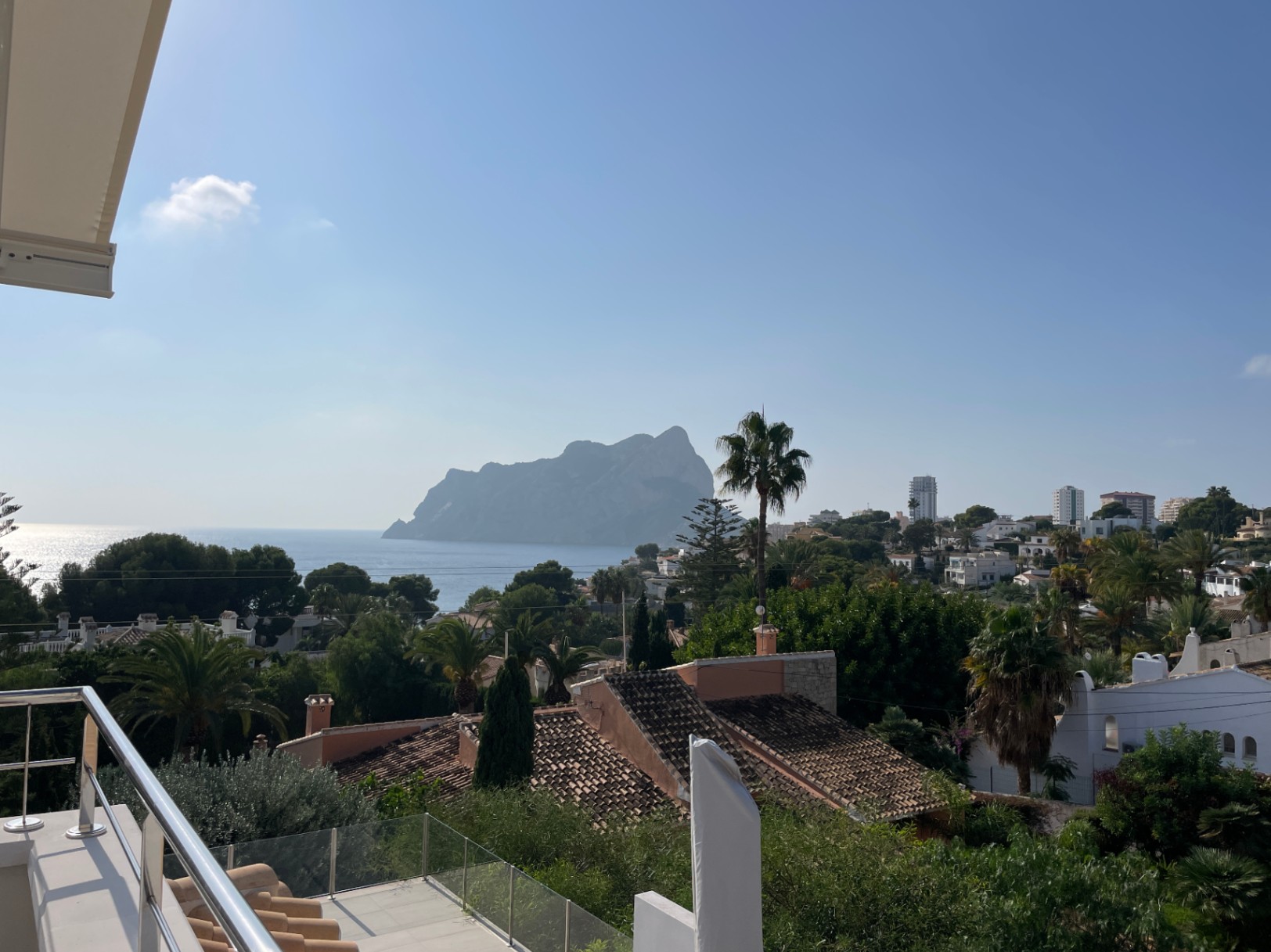 Vista panorámica desde una terraza con barandilla de acero y cristal, orientada hacia el Peñón de Ifach y el mar Mediterráneo en Calpe.