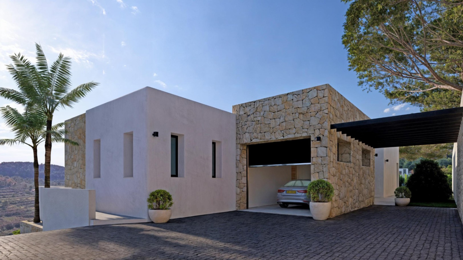 Exterior moderno con garaje revestido en piedra y entrada pavimentada en gris.