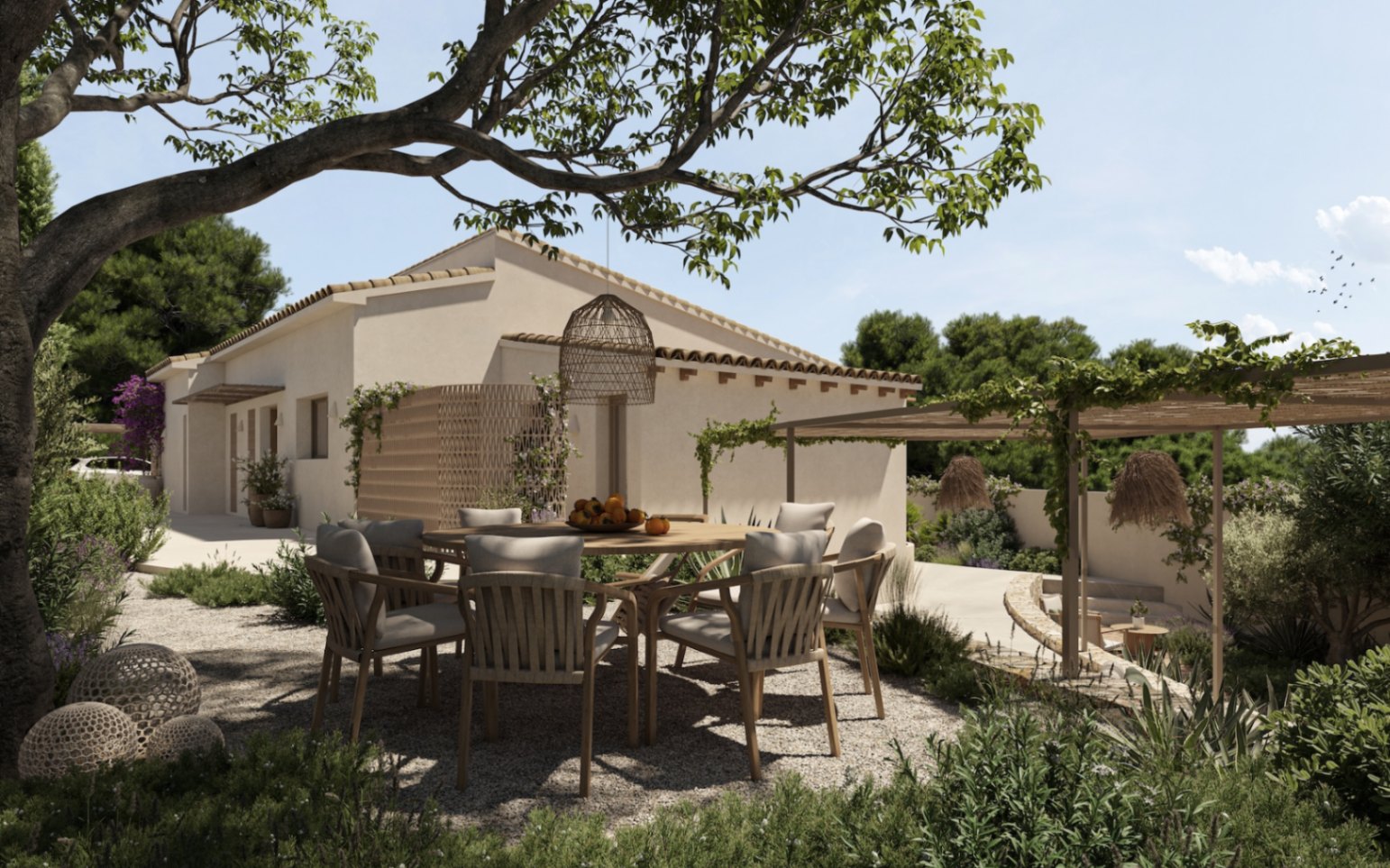 Comedor exterior bajo la sombra de un gran árbol, con mesa circular de madera y sillas de diseño orgánico sobre suelo de grava, junto a la fachada de la villa.