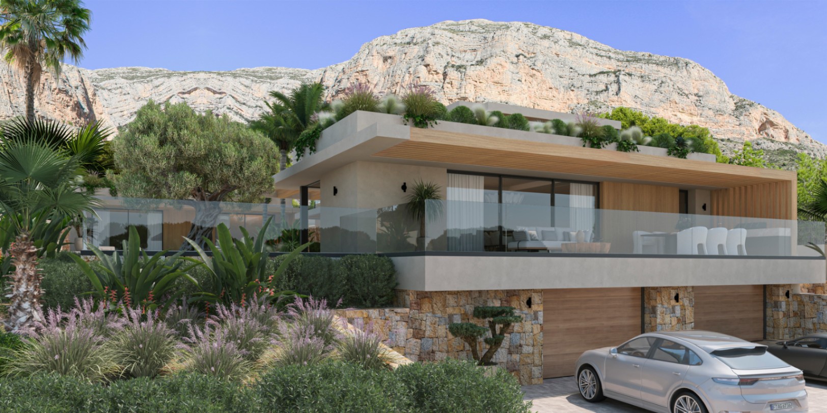 Vista exterior de la villa con fachada de piedra natural y madera bajo el Montgó. Incluye una amplia terraza con barandilla de cristal y acceso al garaje doble.