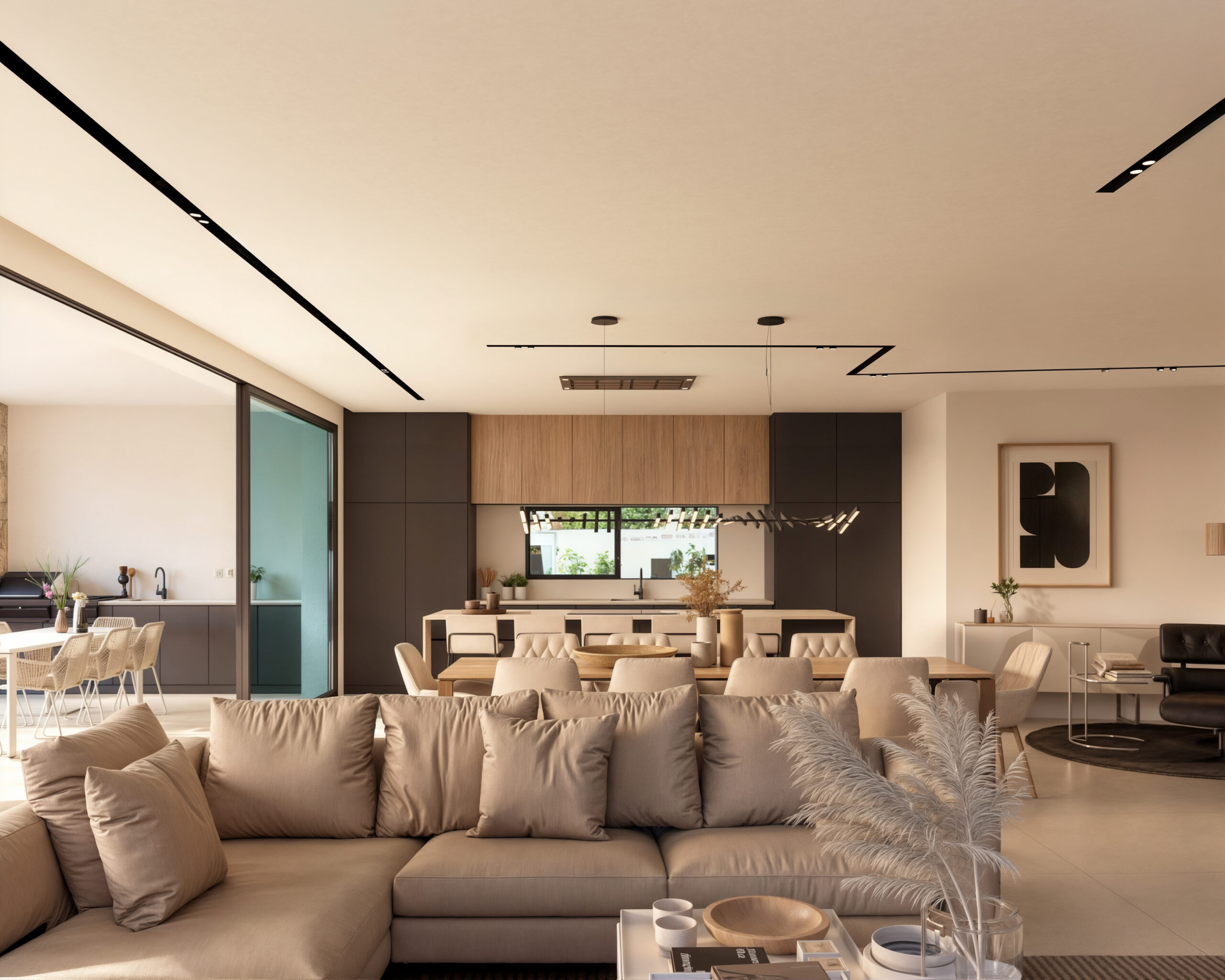 Salón de concepto abierto con un amplio sofá beige, comedor de madera y cocina moderna con armarios oscuros e iluminación técnica empotrada.