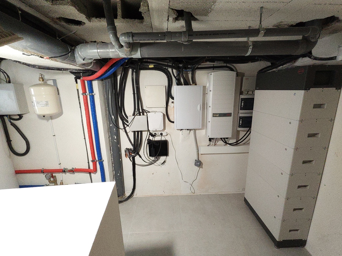 Cuarto técnico con inversor SolarEdge, sistema de almacenamiento por baterías BYD y fontanería organizada con vaso de expansión y tuberías PEX.