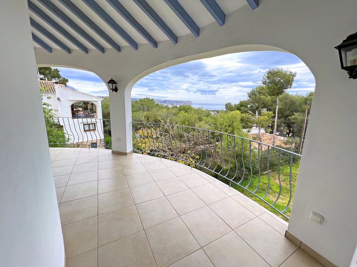 Terraza cubierta con vigas de madera azules, suelo cerámico y barandilla de hierro, ofreciendo vistas panorámicas al mar y al Cabo San Antonio.