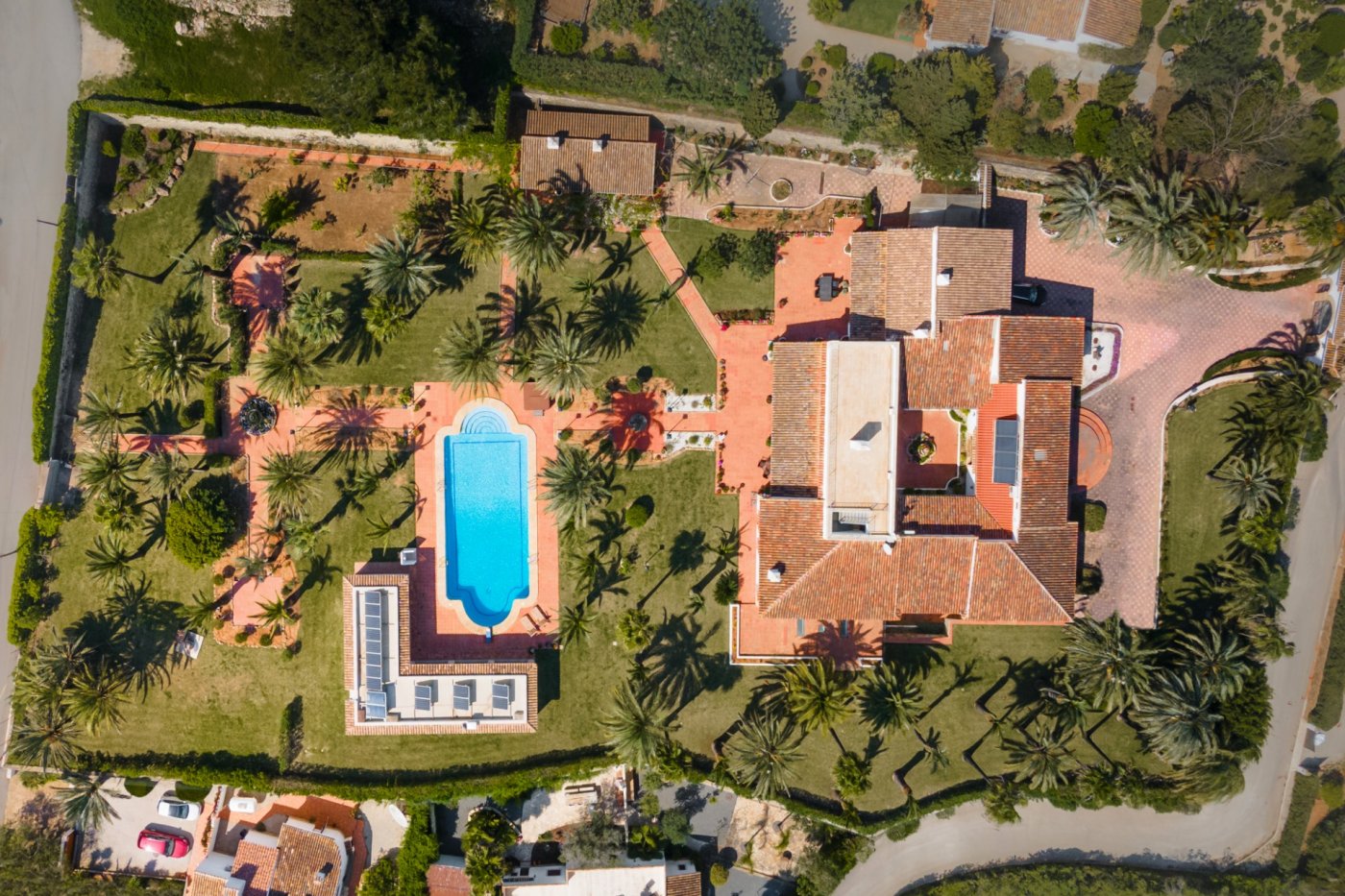 Vista aérea de la finca que destaca la villa con patio central, la gran piscina y el jardín de 5.835 m² con palmeras y senderos de terracota.