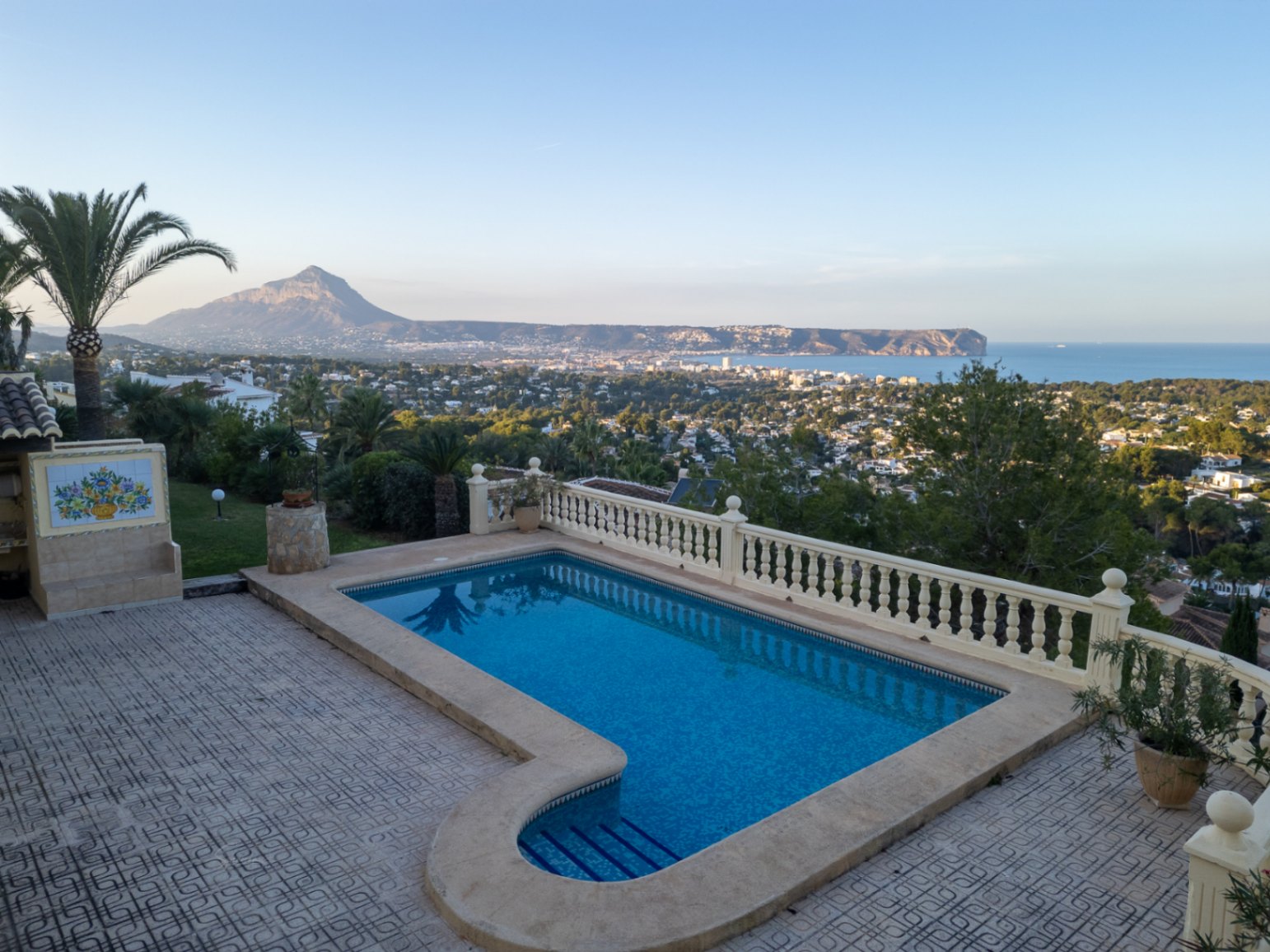 Piscina con escalera romana y balaustrada clásica, con vistas panorámicas a la bahía de Jávea, el mar Mediterráneo y el macizo del Montgó.