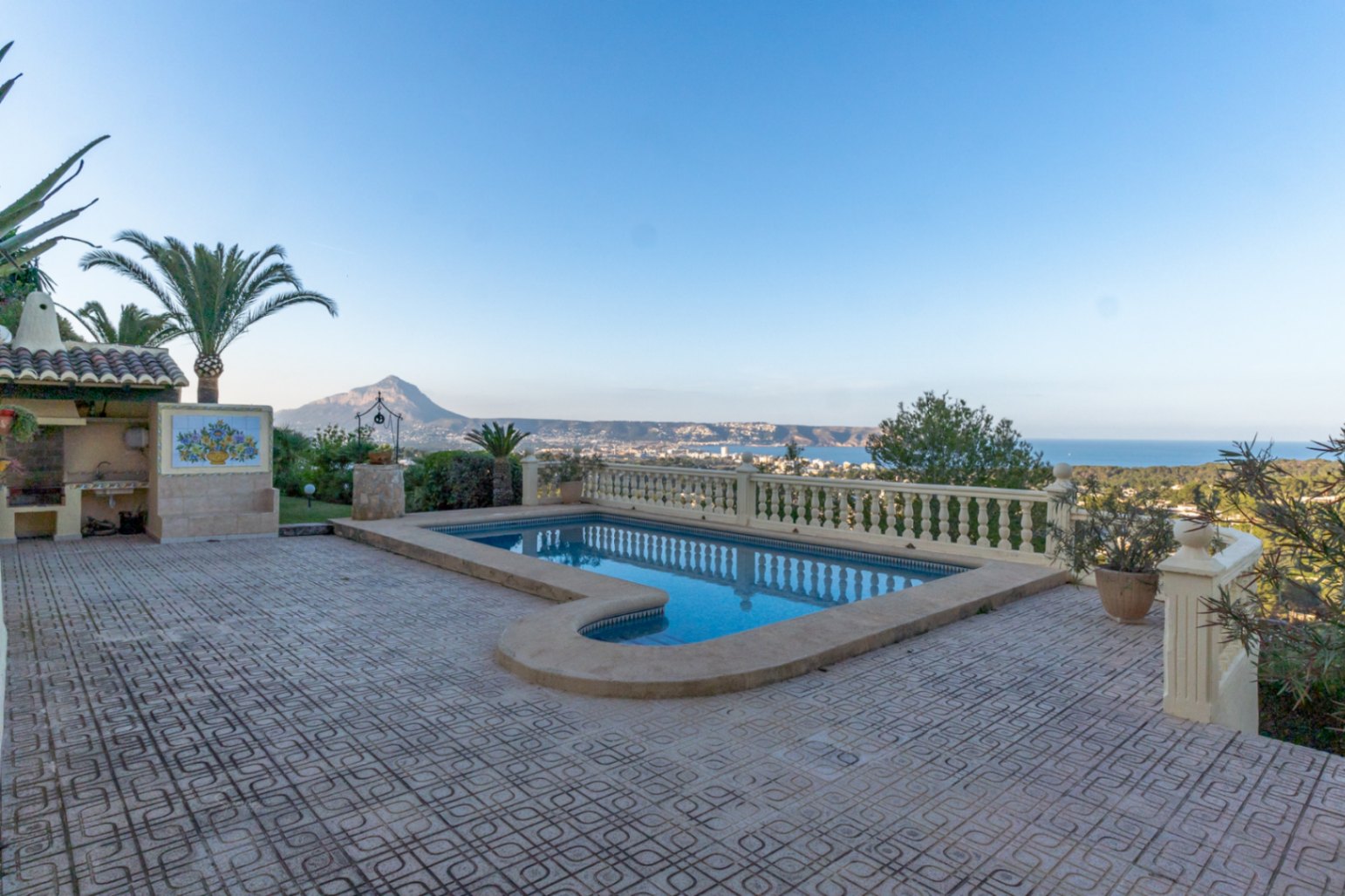 Piscina exterior con escalinata romana y terraza de gres, rodeada por una balaustrada clásica con vistas panorámicas a la bahía de Jávea y al Montgó.