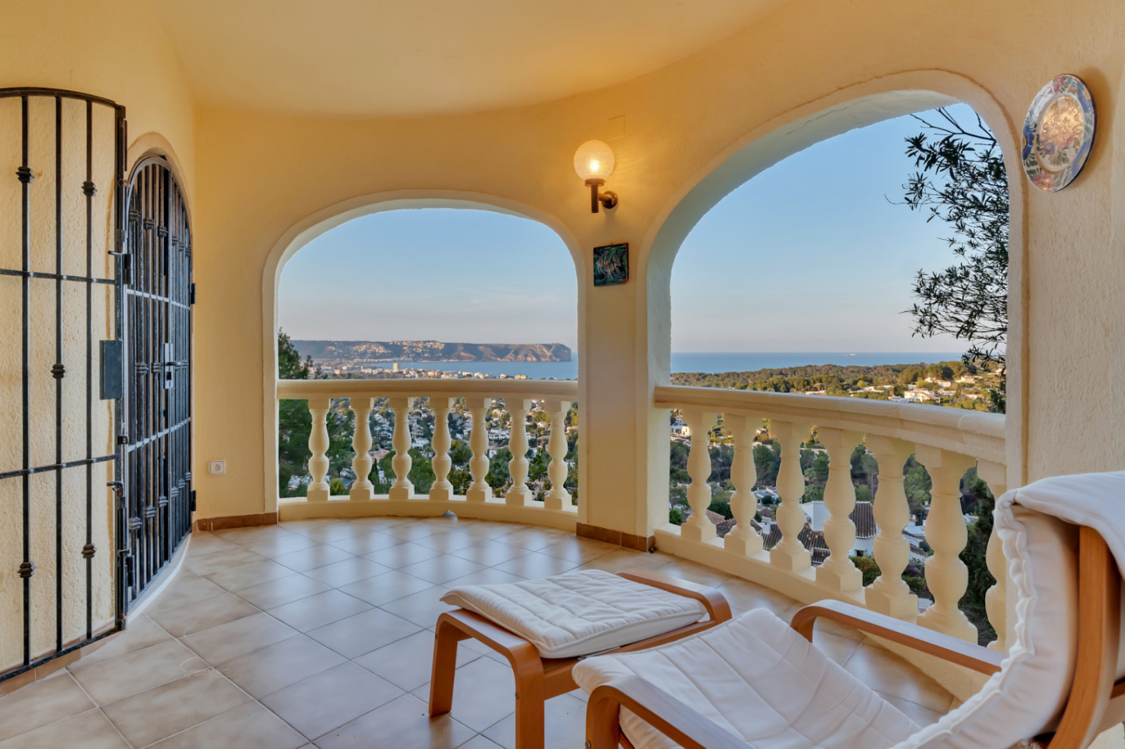Terraza cubierta con arcos y balaustrada clásica, ofreciendo vistas panorámicas a la bahía de Jávea y al Cabo San Antonio sobre un suelo de gres cerámico.