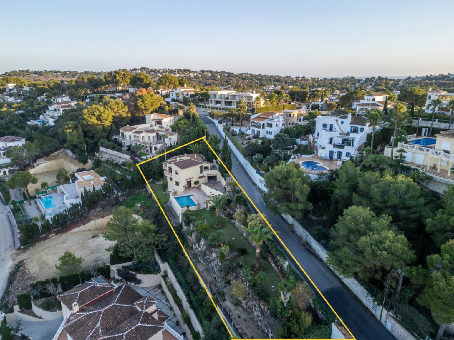Vista aérea de la propiedad delimitada, destacando la villa de estilo mediterráneo, su piscina privada y el jardín aterrazado con palmeras en Costa Nova.