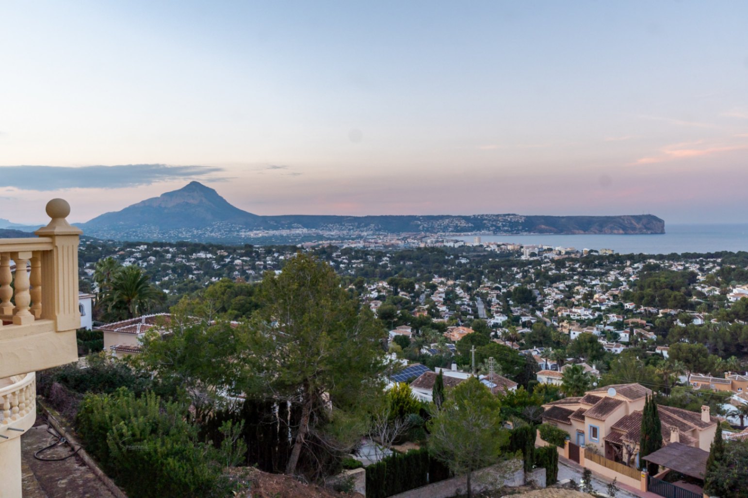 Vistas panorámicas desde la terraza hacia la bahía de Jávea y el Cabo San Antonio, con el monte Montgó al fondo bajo la luz del atardecer.