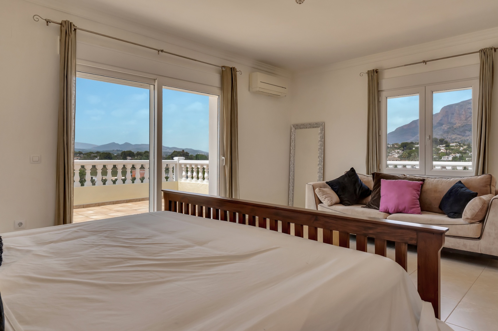 Dormitorio principal con cama de madera, zona de estar y acceso directo a terraza con vistas al Montgó y al valle. Incluye aire acondicionado y suelos cerámicos.