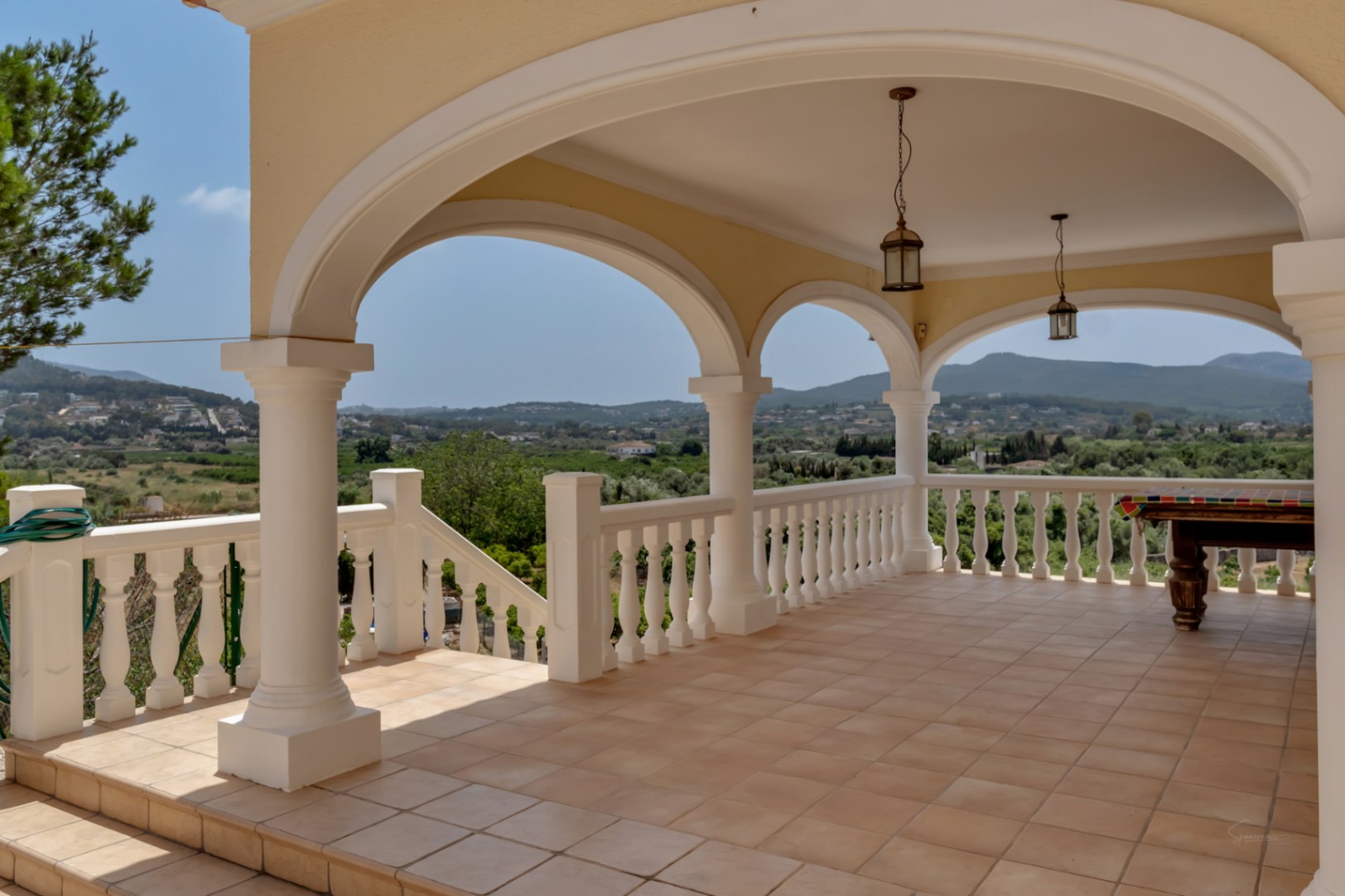 Naya cubierta con arcos, columnas blancas y barandilla de balaustrada. Ofrece vistas panorámicas al valle, suelo de gres y zona de ocio con mesa de billar.