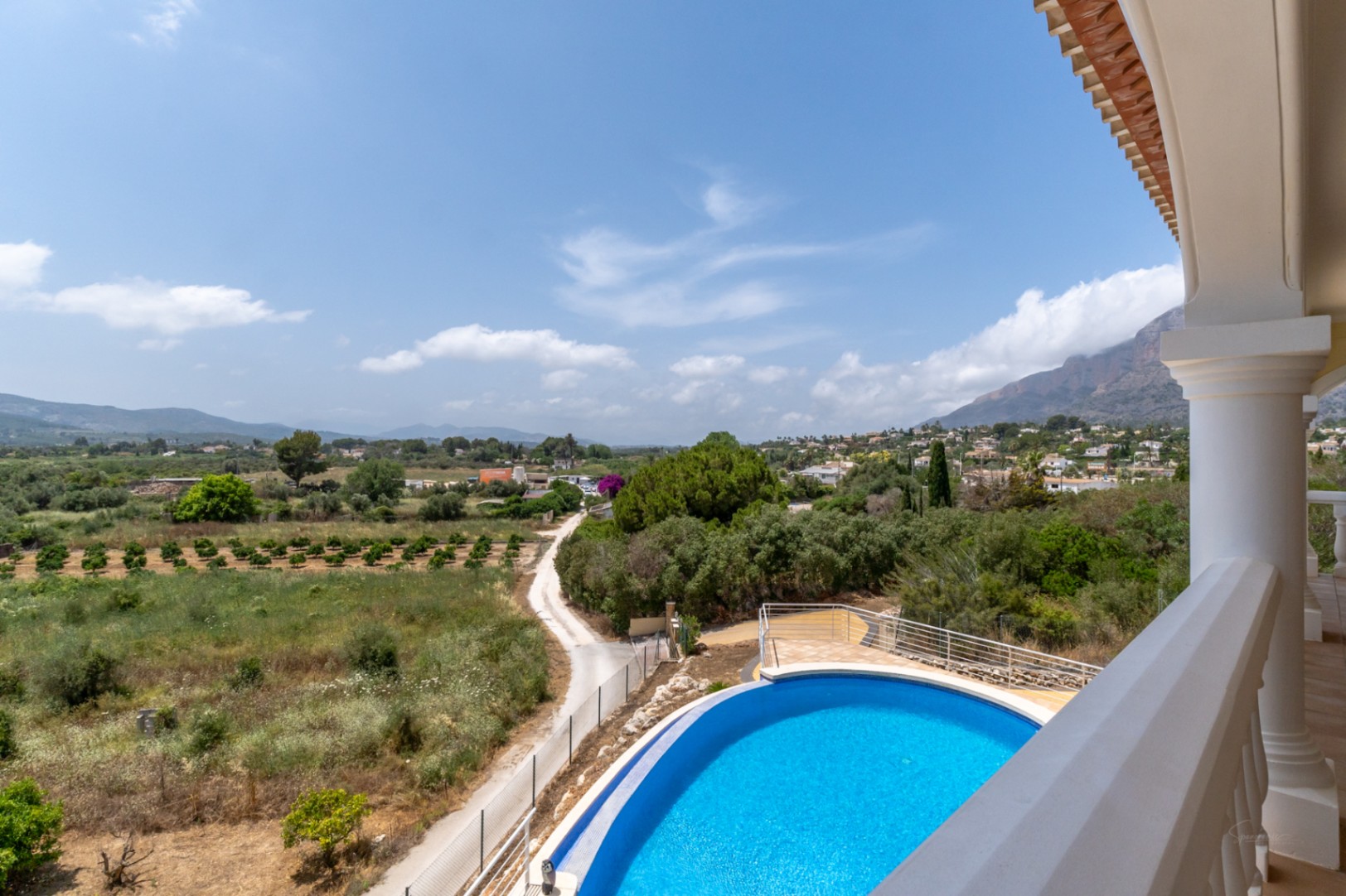 Vista desde la terraza superior que muestra la piscina ovalada y vistas panorámicas de 180º hacia el valle y el macizo del Montgó.
