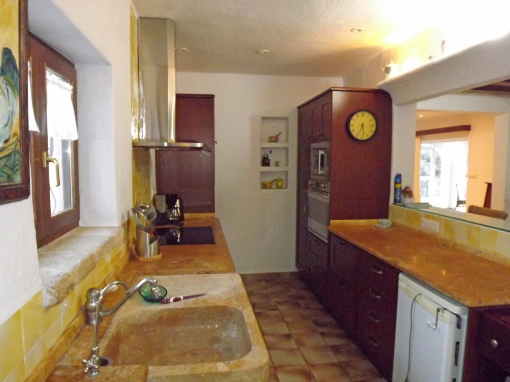 Cocina de estilo rústico con fregadero de piedra maciza, encimeras de mármol, armarios de madera oscura y campana extractora de acero inoxidable.