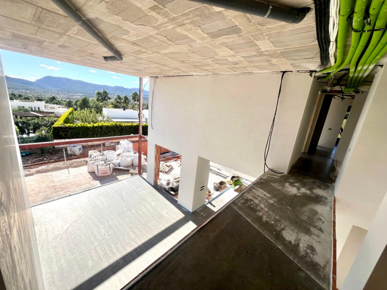 Avance de obra que muestra la estructura de doble altura, instalaciones técnicas vistas y la amplia terraza con vistas panorámicas al Montgó.