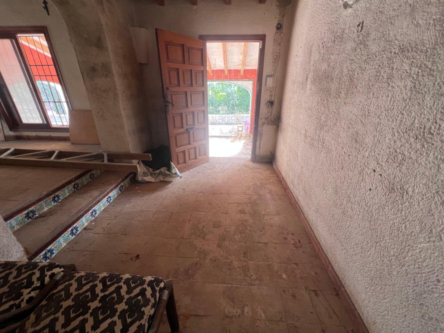 Entrada con suelos de barro, puerta de madera maciza y escalones con azulejos tradicionales. Espacio luminoso con gran potencial de reforma integral.