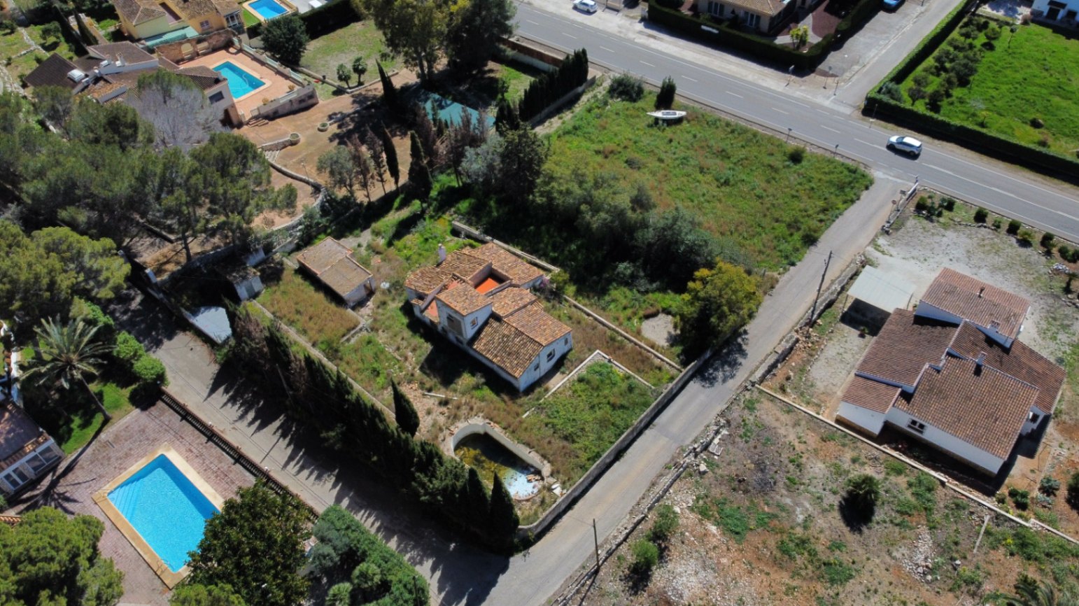 Vista aérea de la parcela de 2.895m2 en Jávea, destacando la vivienda de estilo tradicional, la piscina para rehabilitar y la extensión de terreno con vegetación mediterránea.