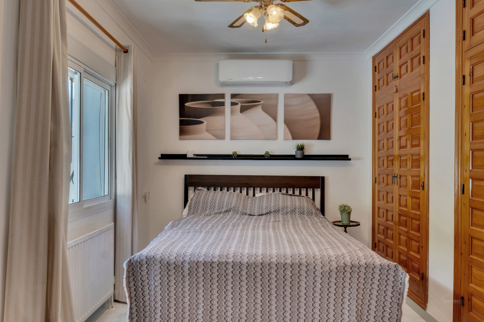 Dormitorio con armarios empotrados de madera tallada, aire acondicionado, calefacción por radiador y ventana de doble acristalamiento.