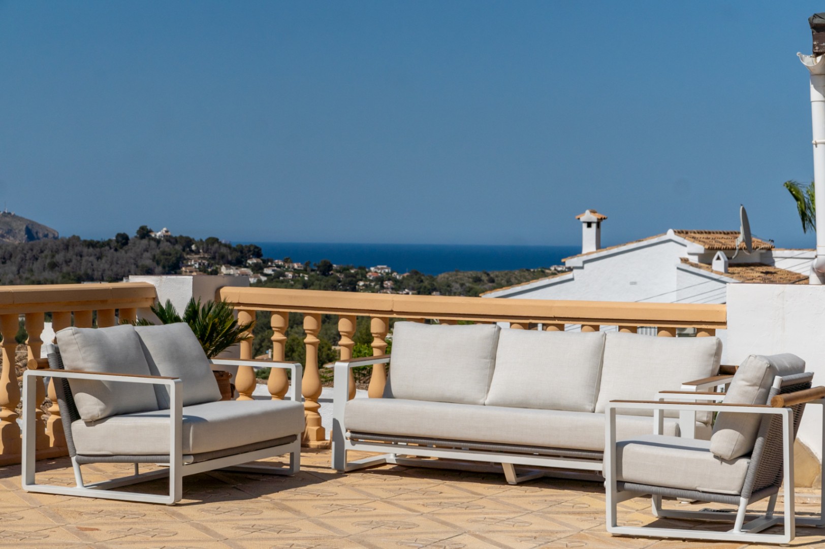 Terraza elevada con mobiliario de diseño moderno y vistas panorámicas al mar. El espacio cuenta con suelos cerámicos decorados y una barandilla de balaustres de estilo mediterráneo.
