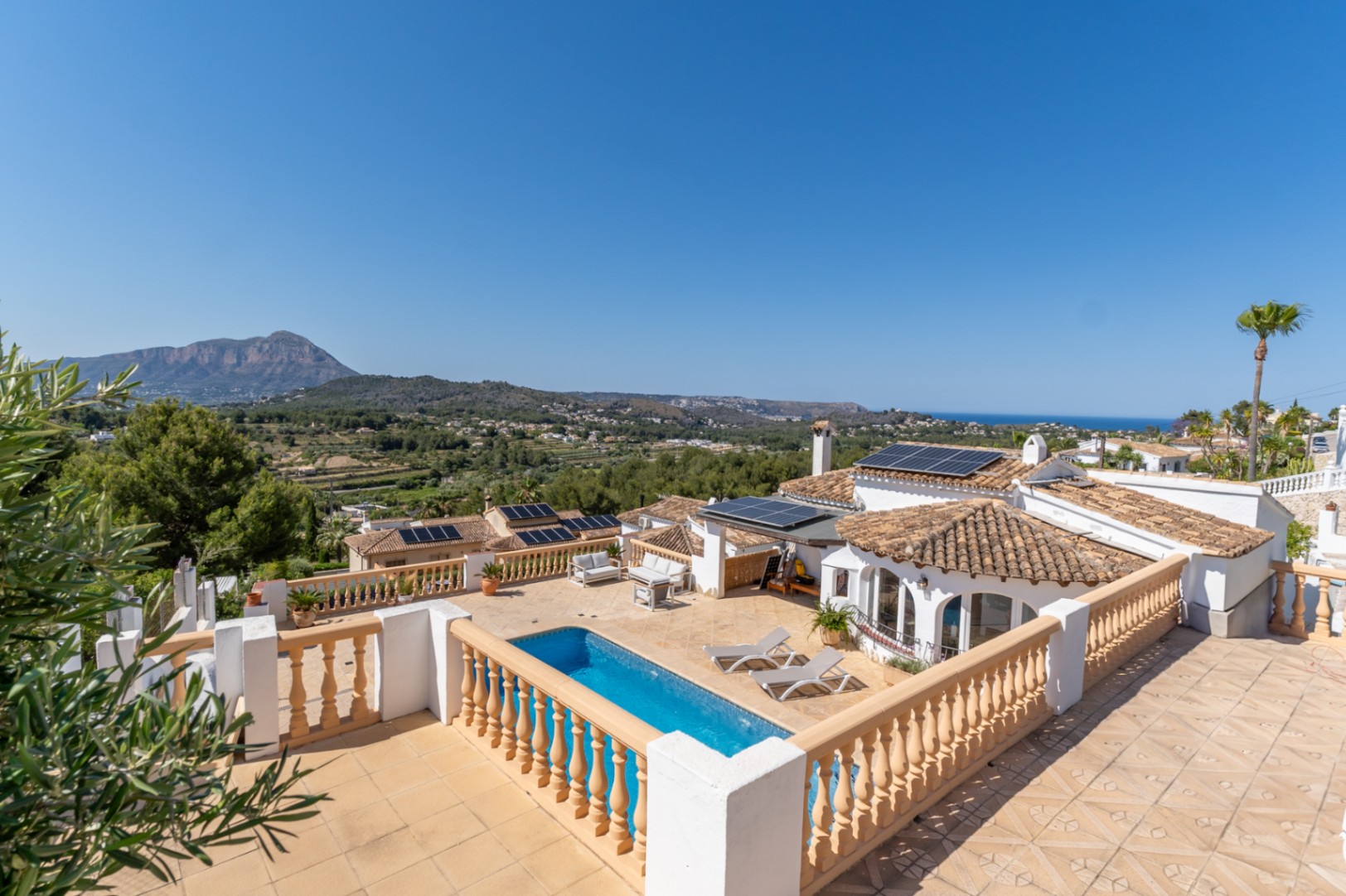 Terraza exterior con piscina, vistas despejadas al Montgó y al mar, destacando la instalación de placas solares en la cubierta tradicional.